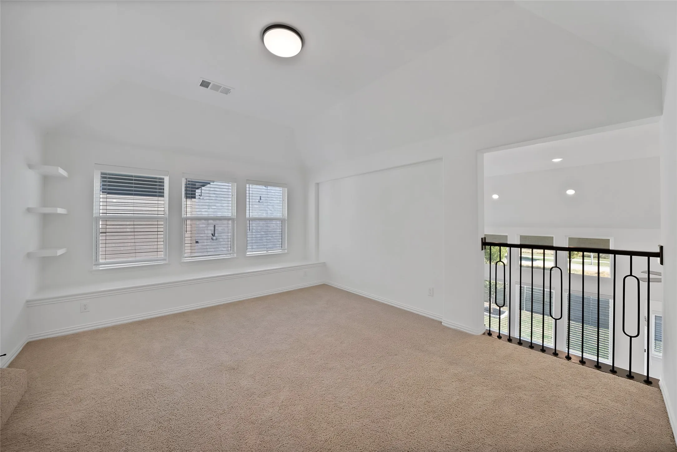 Vaulted ceiling, built-in wall shelving, integrated window bench seating, and decorative black metal railing