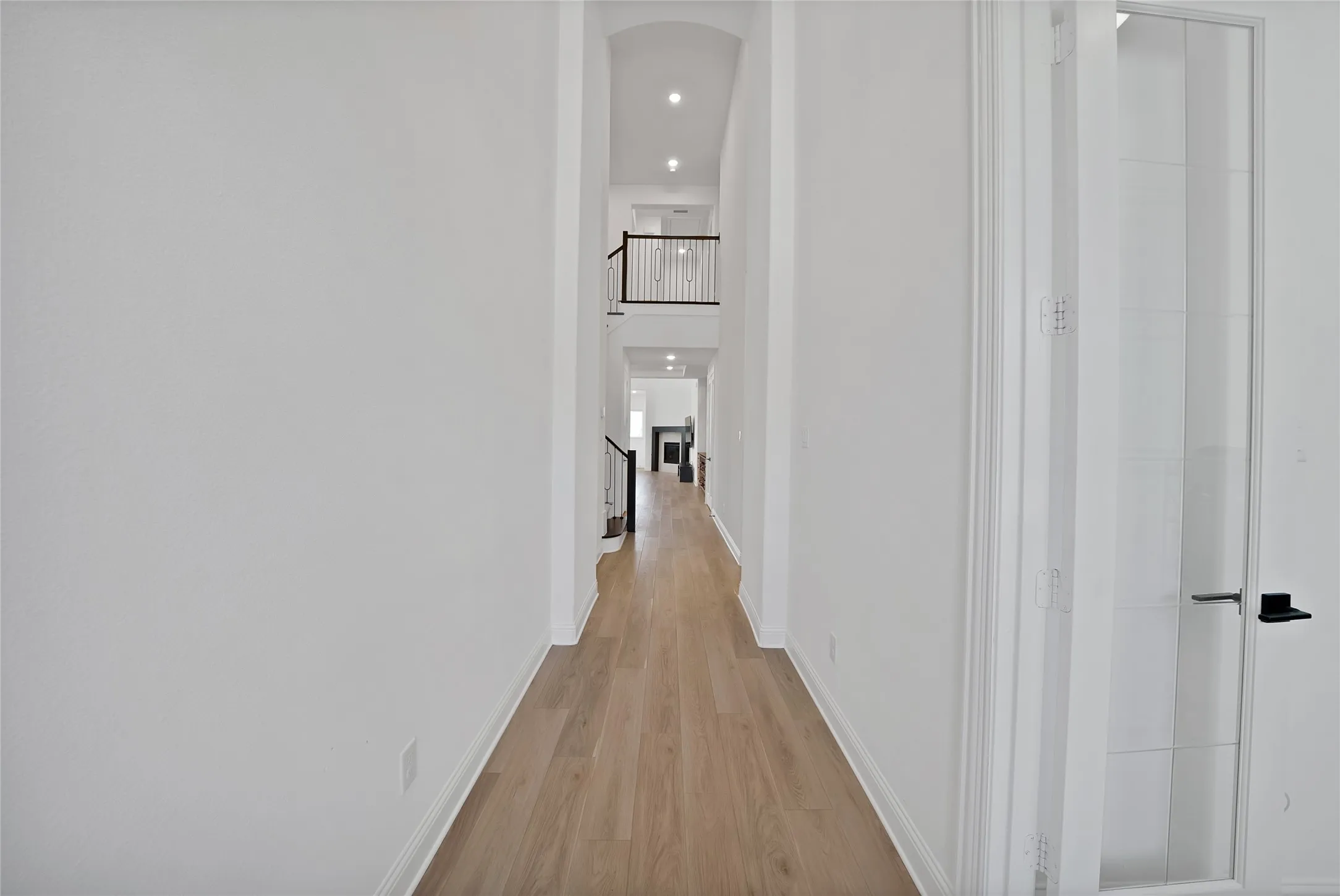 Vaulted ceilings, wood-finish flooring, recessed lighting, and a staircase featuring metal balusters