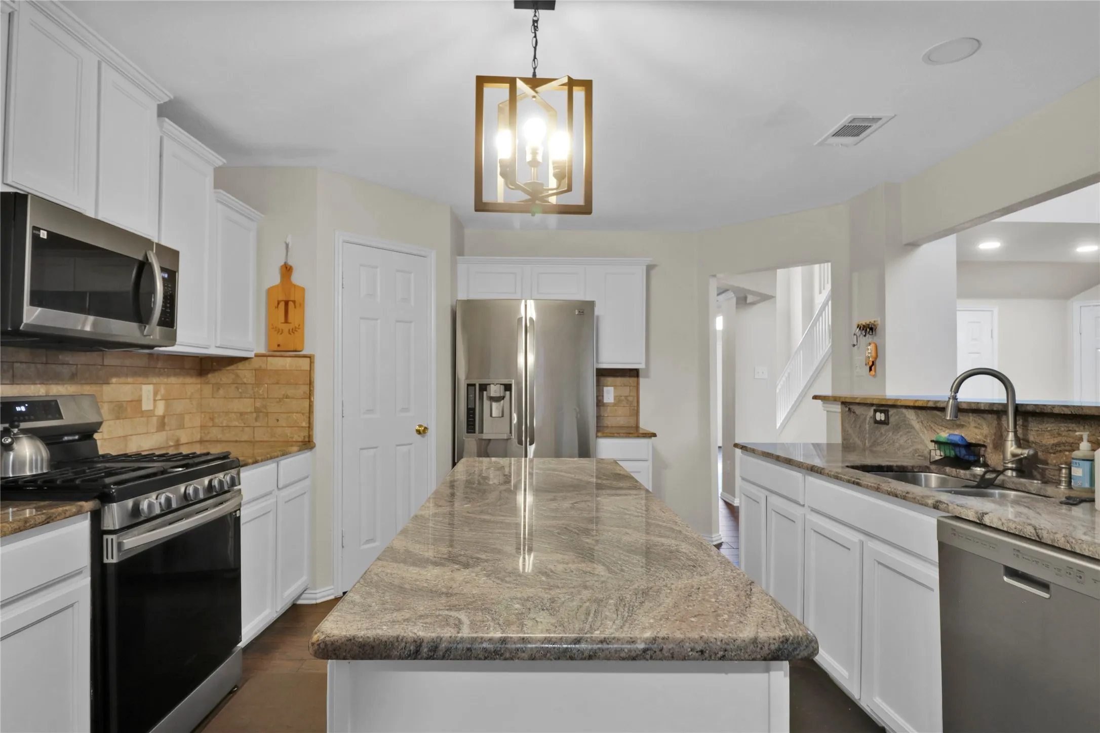Kitchen with granite counters, long island for extra prep space, and SS appliances.