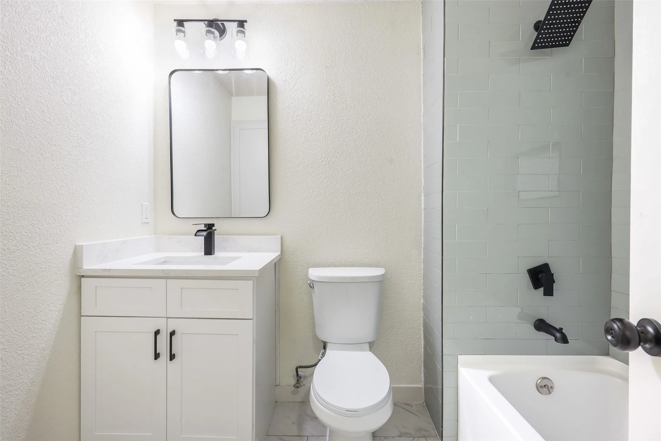 White vanity with a light-toned countertop, black faucet, and rectangular mirror
