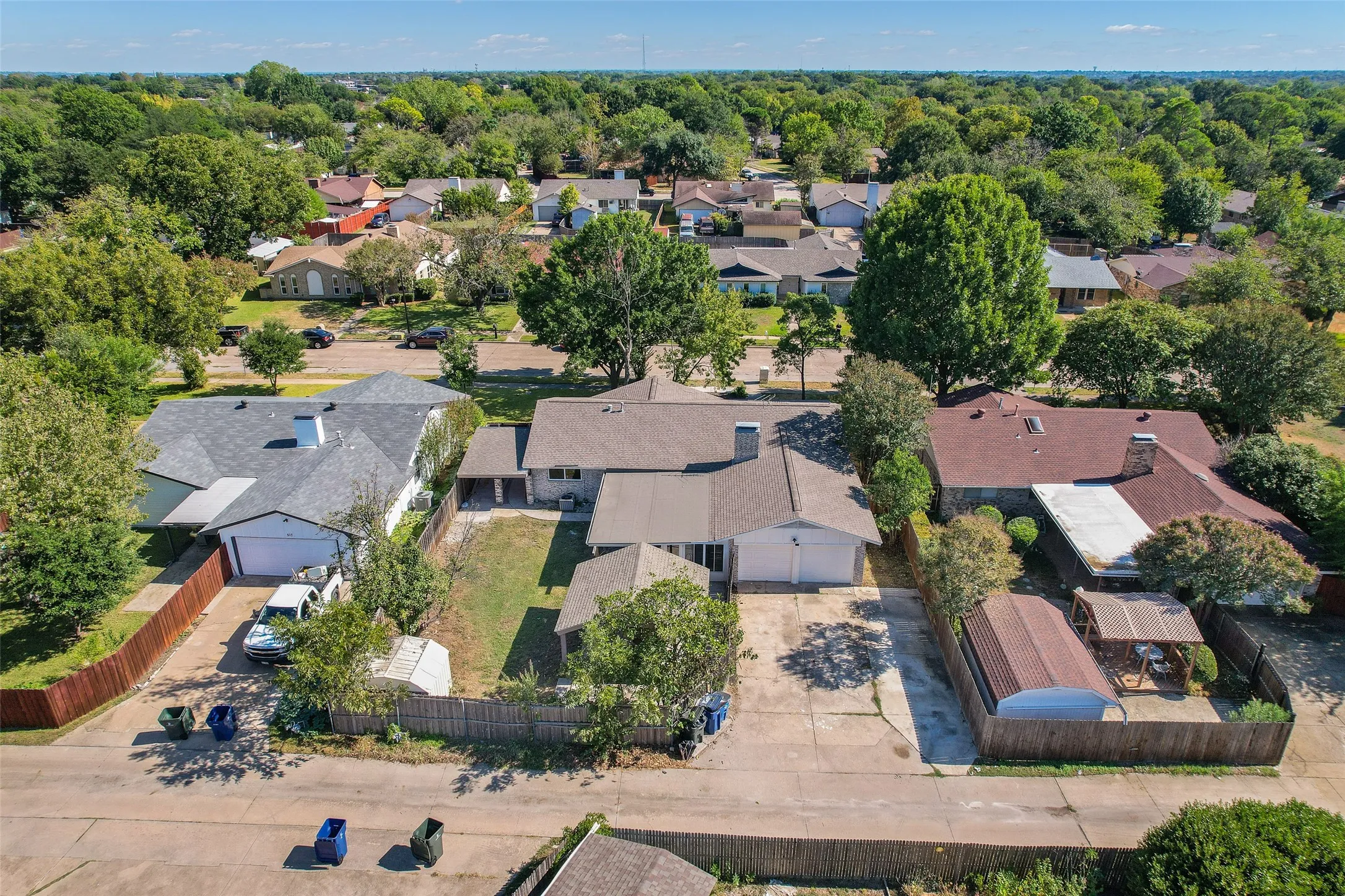 Expansive residential neighborhood with mature trees, offering a private backyard area and paved driveway