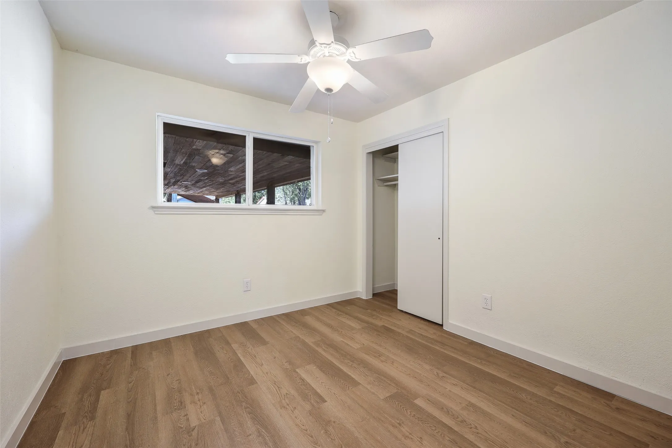 Smooth-finish walls, wood-finish flooring, and a ceiling fan with integrated lighting