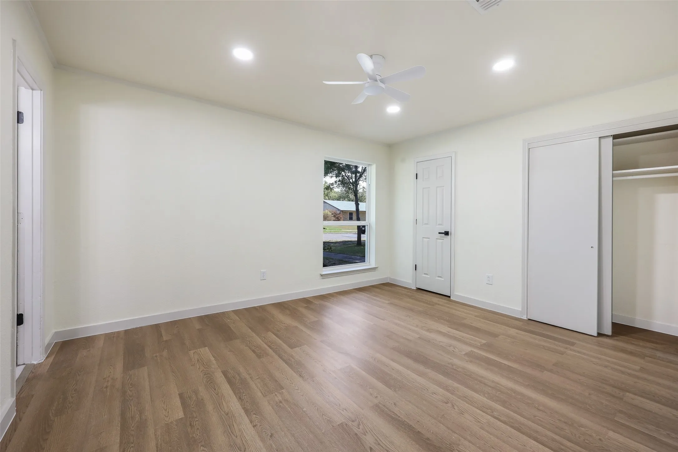 Wood-finish flooring with recessed lighting, ceiling fan, and sliding closet doors