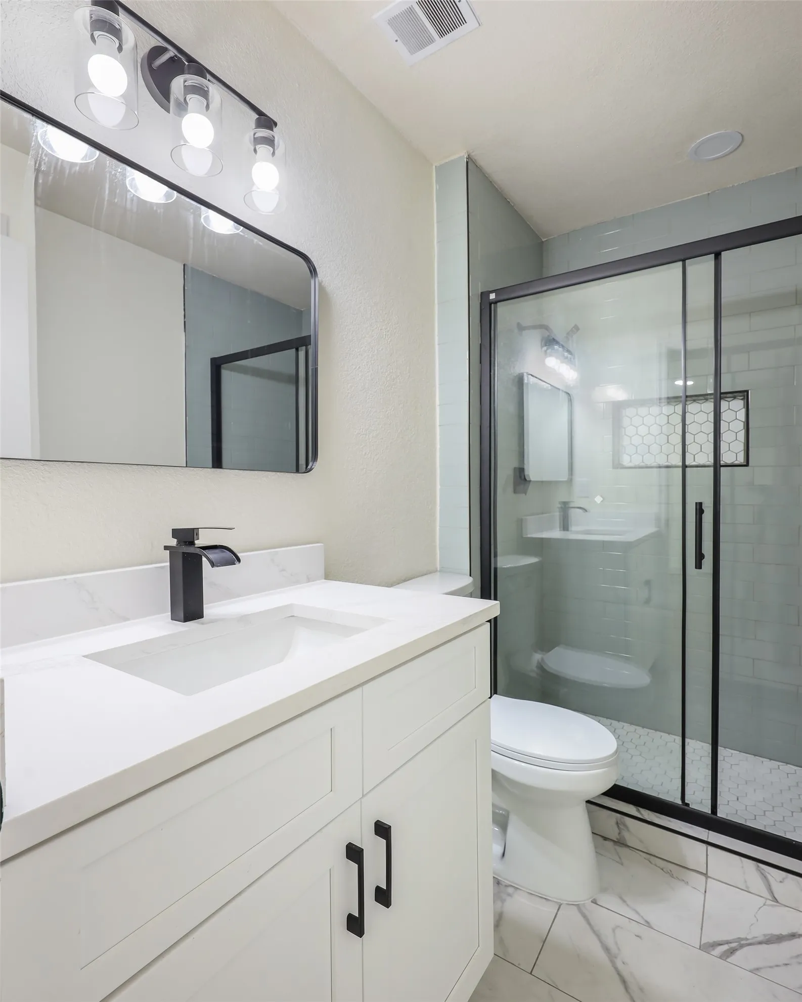 White vanity with integrated sink, black waterfall faucet, and white countertop