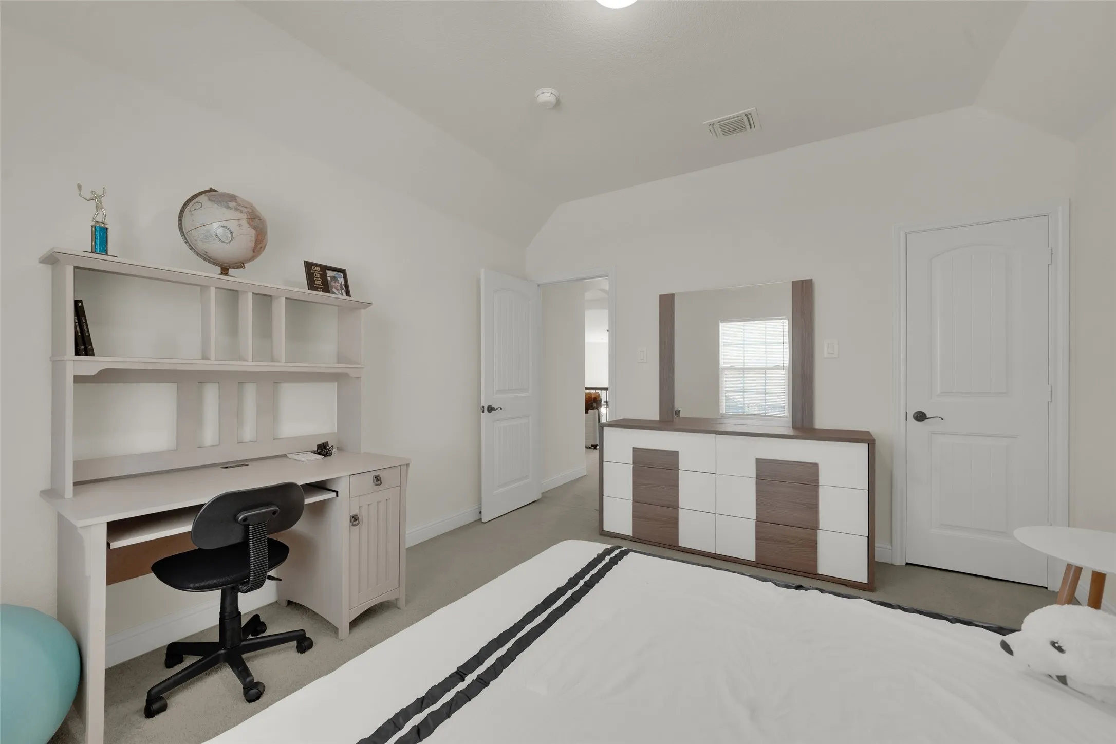 Neutral-toned interior space featuring vaulted ceilings, plush carpeting, and two six-panel interior doors with brushed nickel hardware