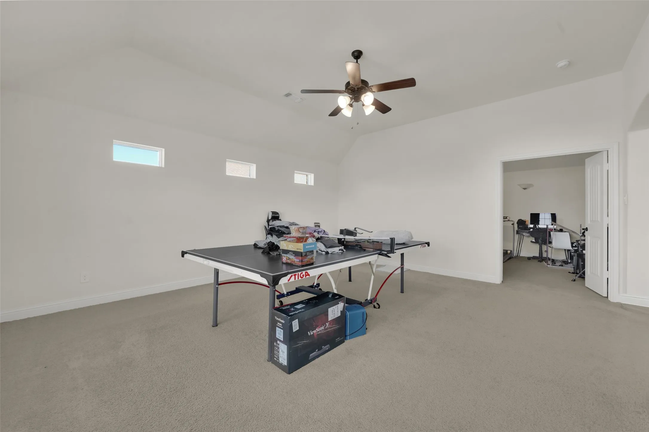 Vaulted ceilings featuring a central multi-blade light fixture and three rectangular transom windows