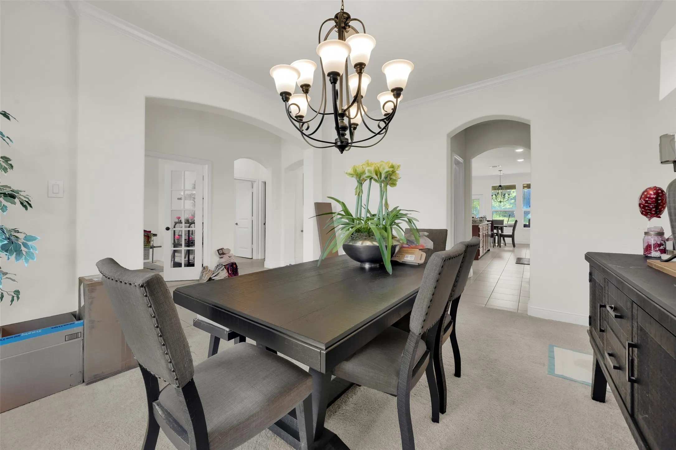 Multi-arm chandelier with frosted glass shades, arched entryways, and french doors with glass panes