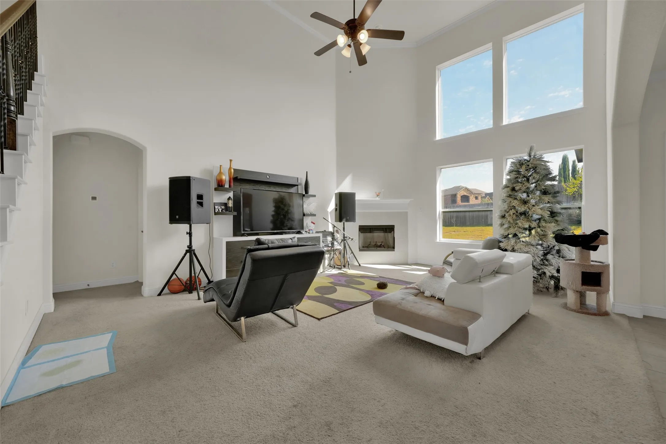 Expansive living area featuring vaulted ceilings, a fireplace with a mantel, stacked windows, and a ceiling fan