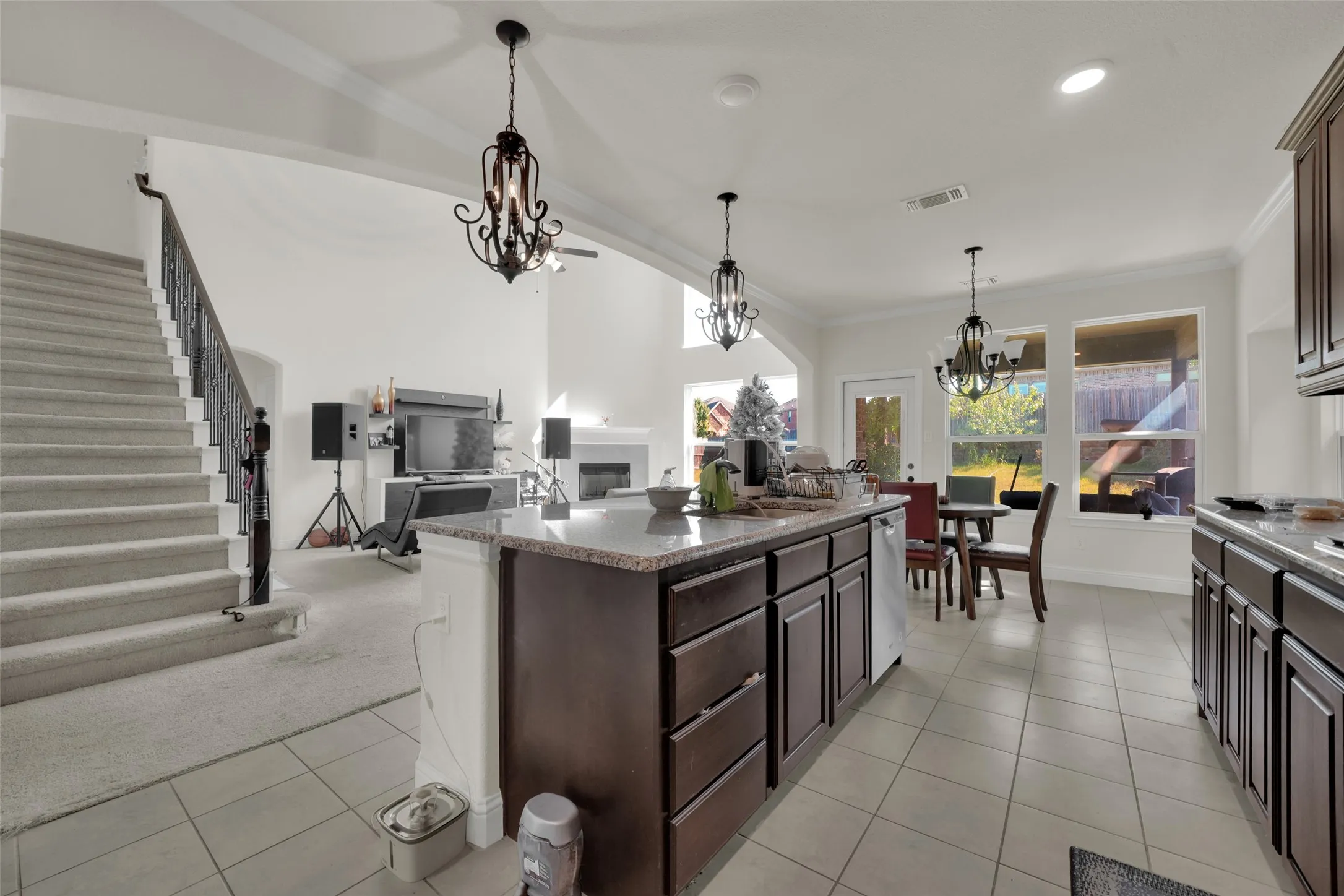Kitchen featuring an island with stone-finish countertops, dark wood cabinetry, recessed lighting, wrought-iron chandeliers, and ceramic tile flooring