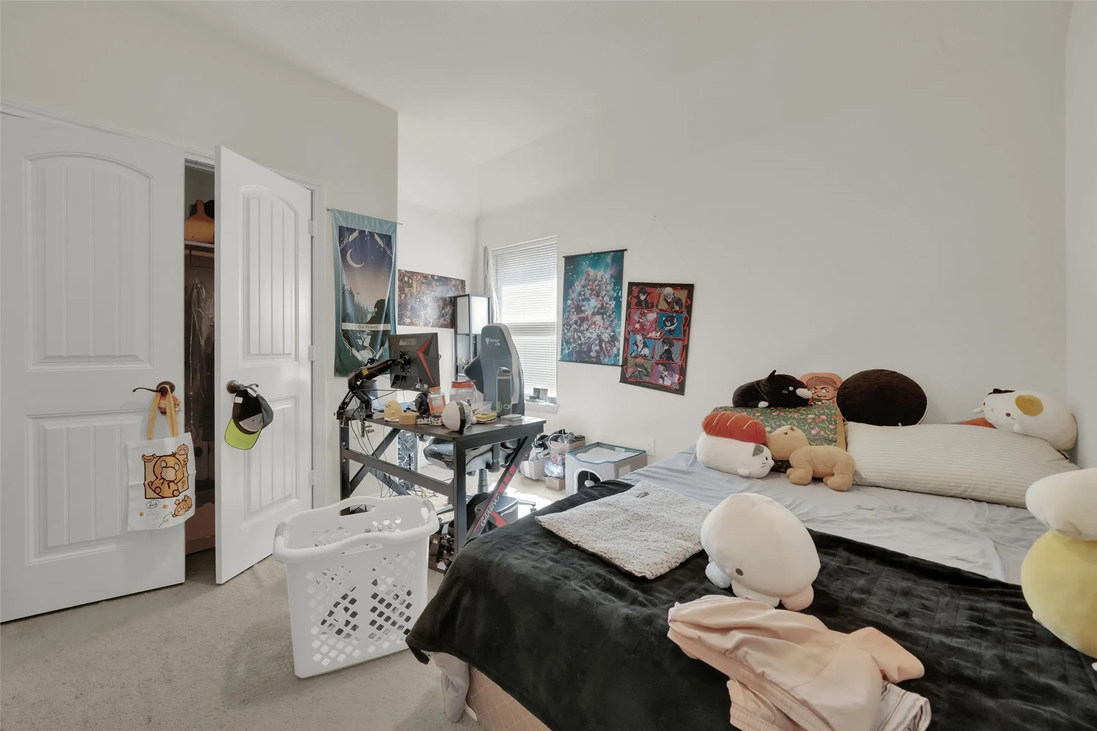 Neutral-toned interior space featuring light carpeting, crisp white wall finishes, an interior closet with double-panel doors, and a natural light source via a window