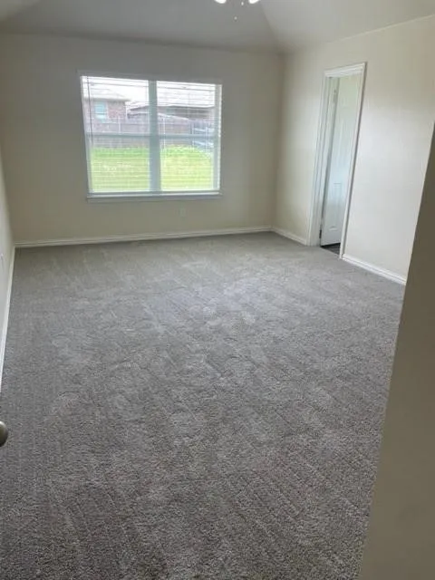 Interior space featuring neutral wall tones, wall-to-wall carpeting, vaulted ceiling, and a large window