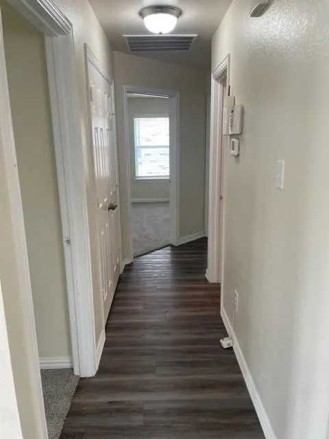 Hallway featuring wood-finish flooring, neutral wall paint, and overhead flush-mount lighting