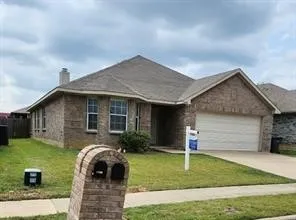 Single-story residence featuring a full brick exterior, a multi-gabled roofline, an attached two-car garage, and a masonry mailbox