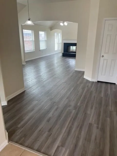 Wood-finish flooring, vaulted ceilings, and a fireplace with a dark-hued hearth