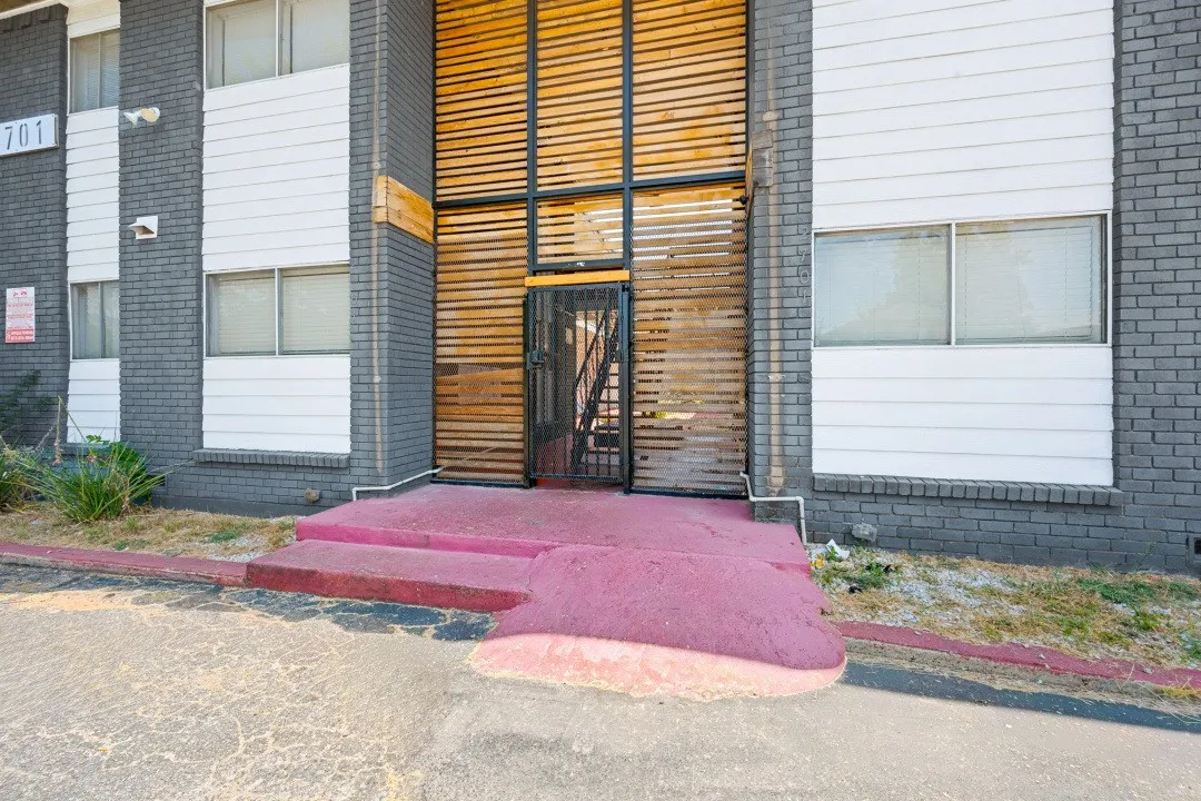 Exterior facade featuring a dark brick finish, horizontal siding, and a decorative wood-slat screening element surrounding the entrance