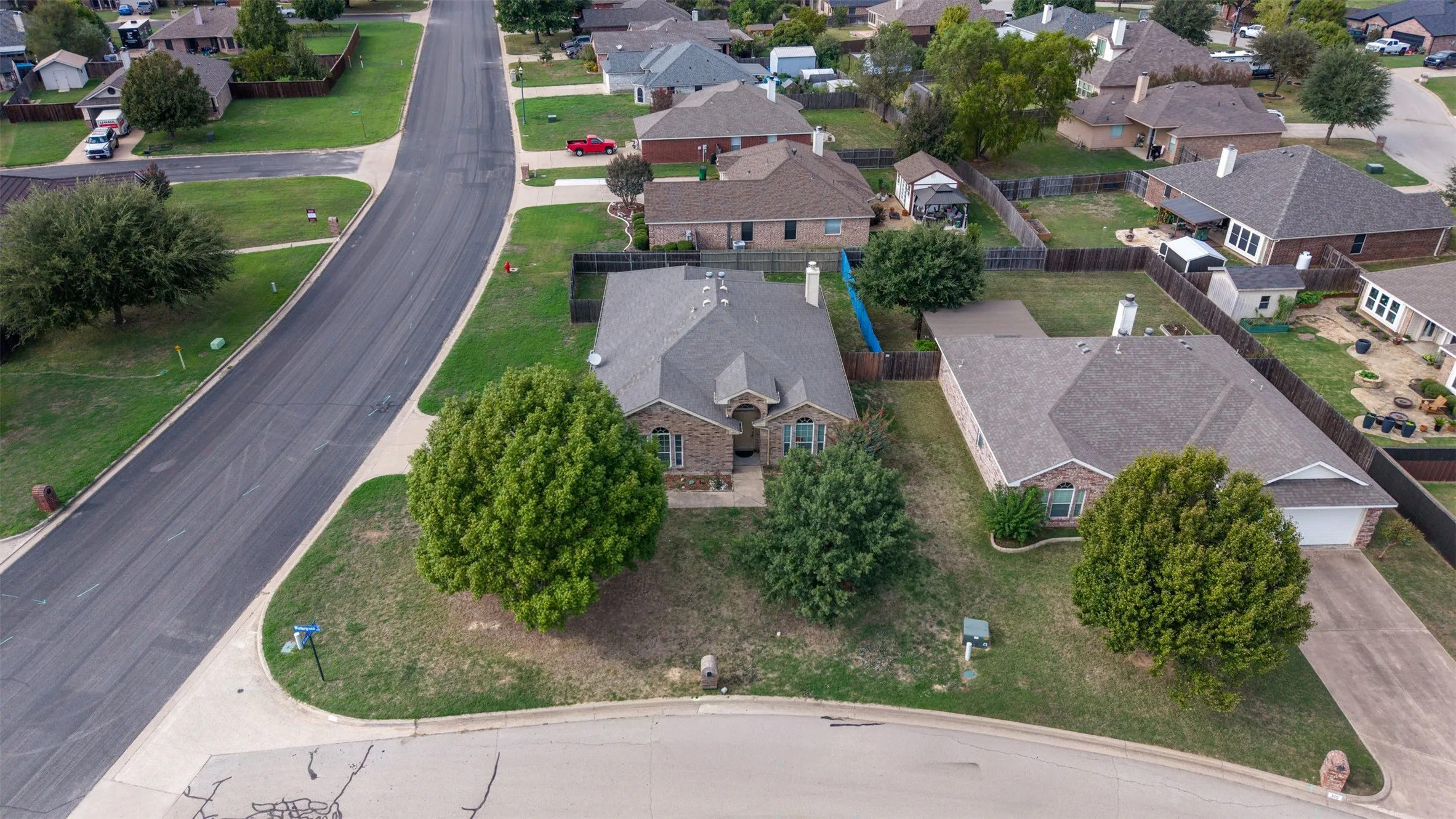 Corner lot property featuring a masonry exterior, a multi-gable roofline, and established mature trees