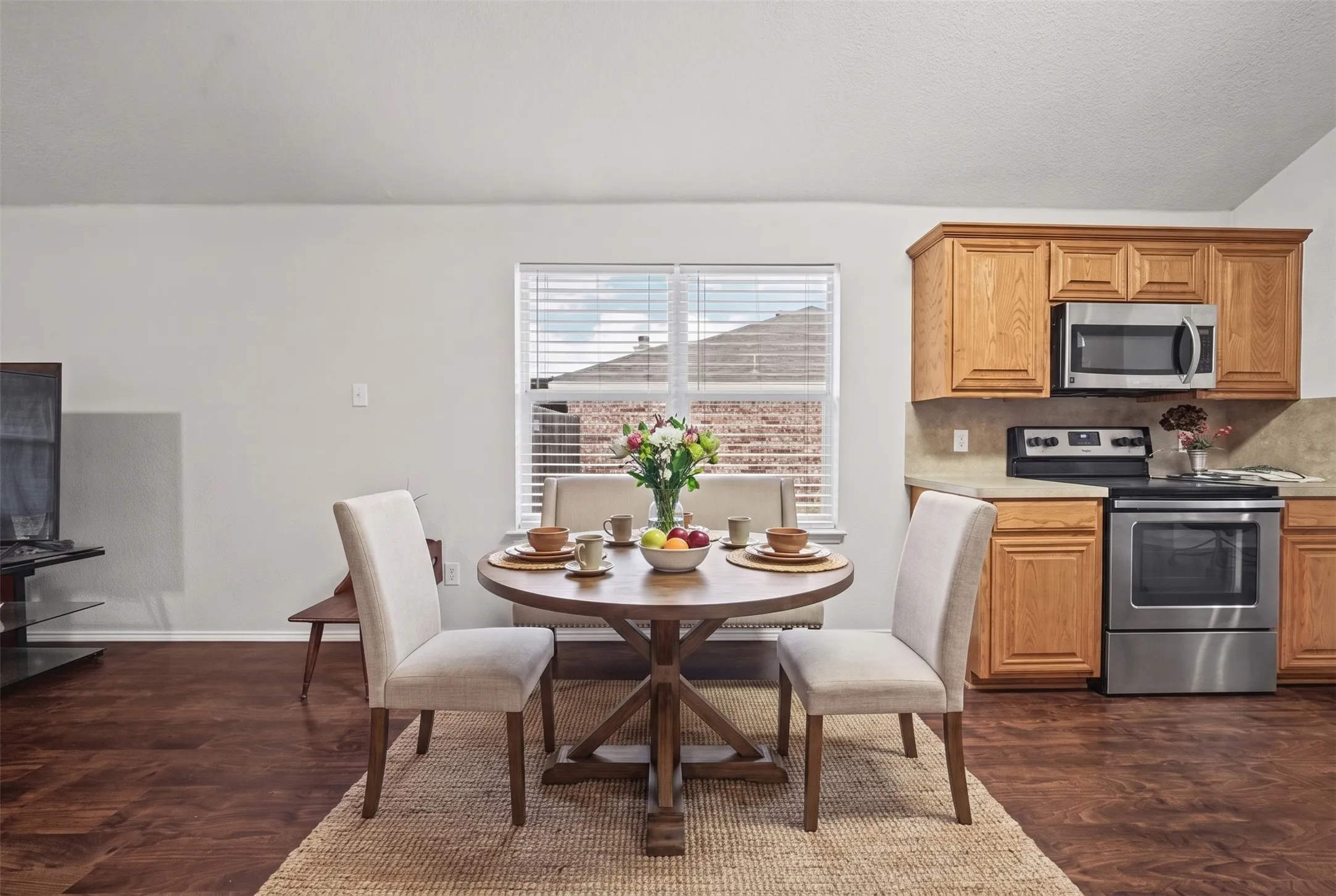 Kitchen featuring wood cabinetry, stainless steel appliances, and wood-finish flooring with a multi-pane window