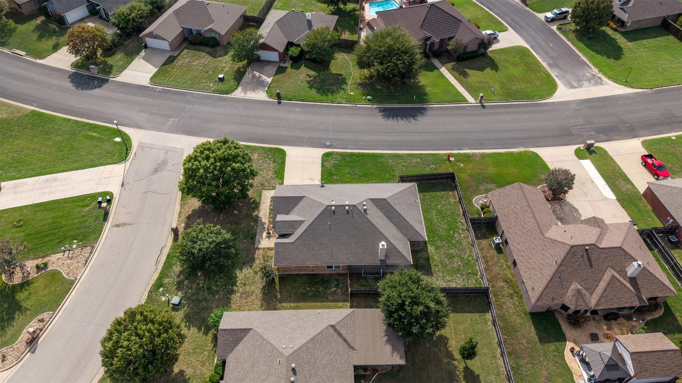 Aerial perspective of a corner lot property featuring a multi-gable roofline, exterior chimney, and rear-fencing