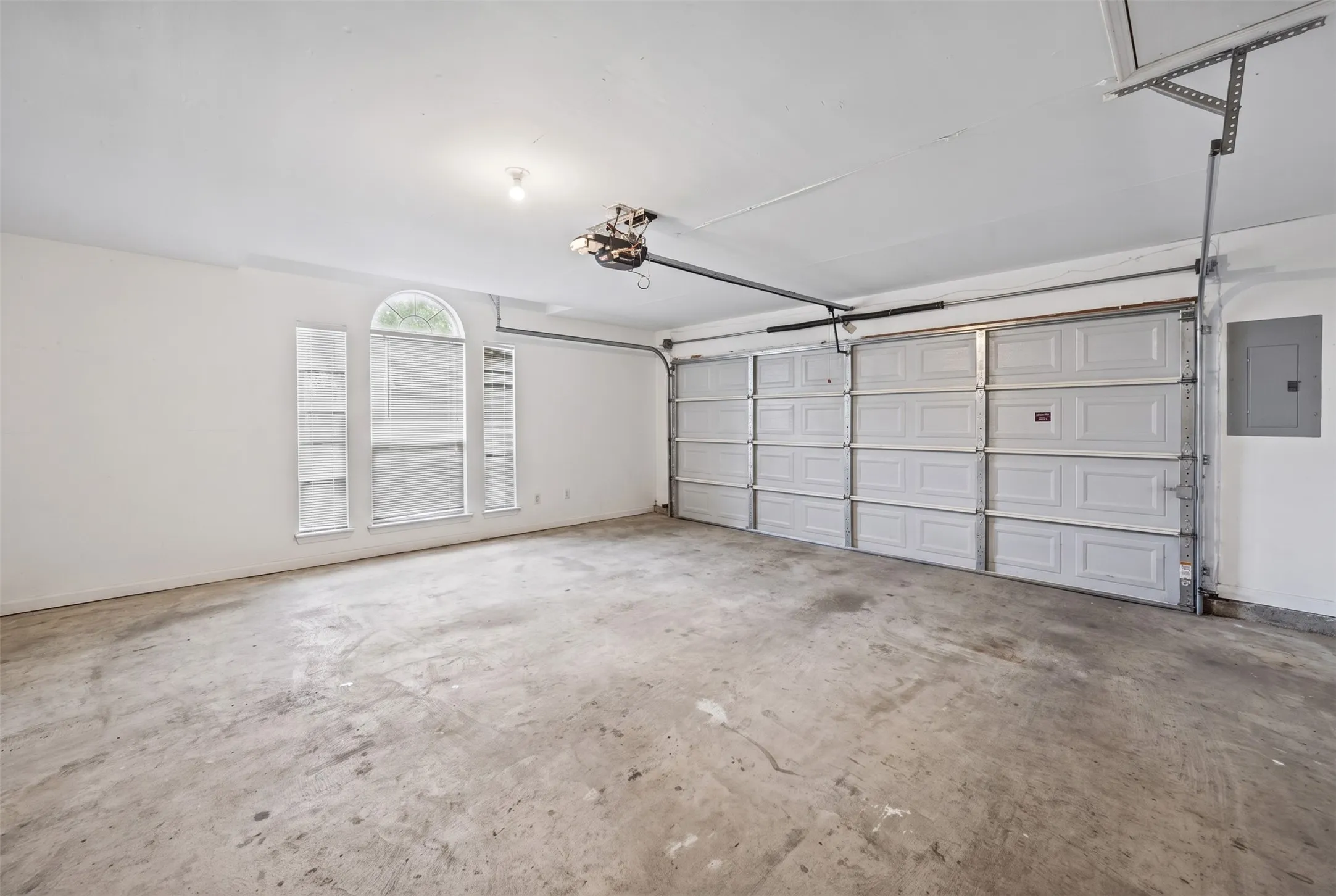 Multi-car garage featuring a segmented overhead door, arched window configuration, and concrete flooring