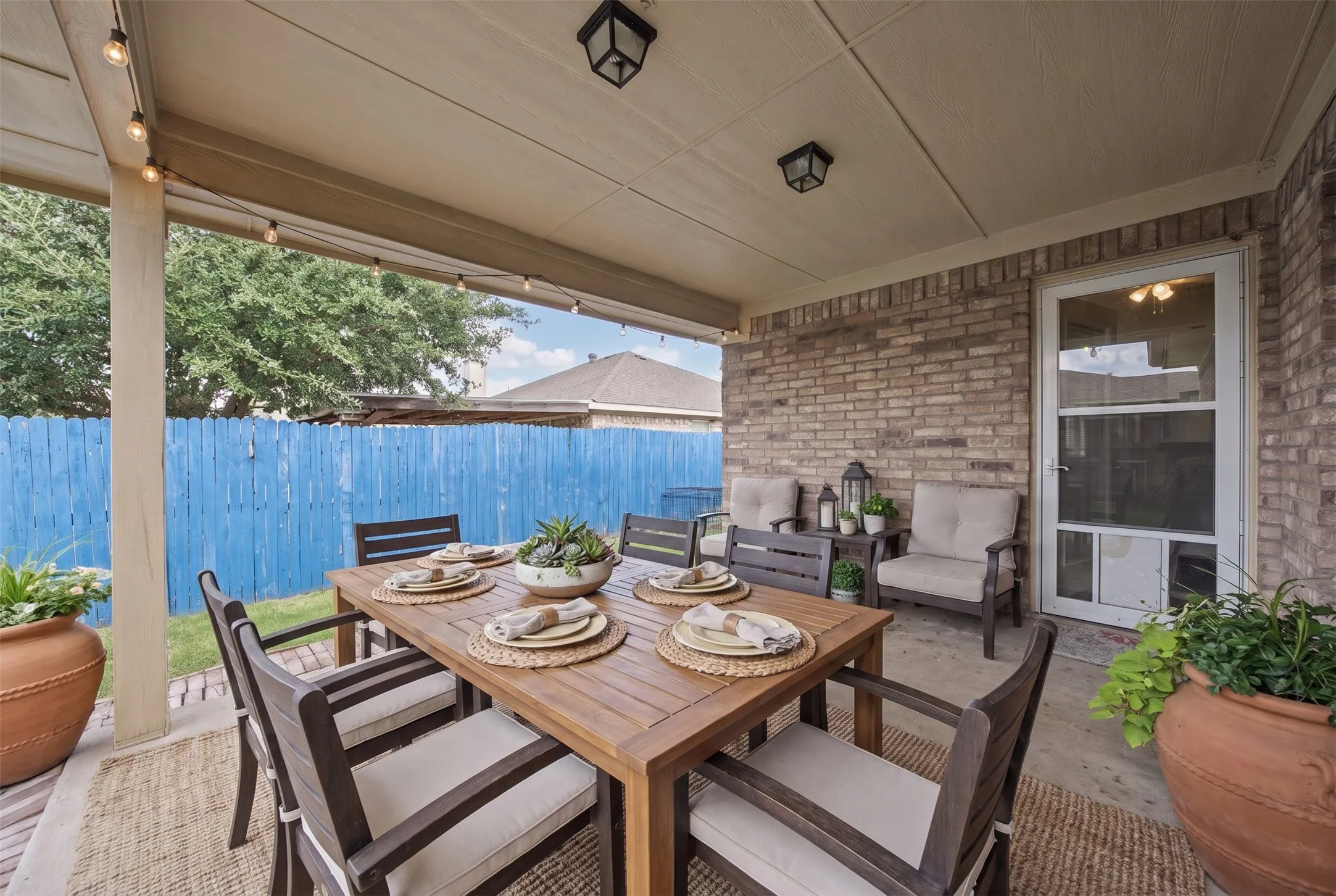 Covered patio featuring a concrete floor, brick exterior wall, recessed lighting, and a glass-paneled door
