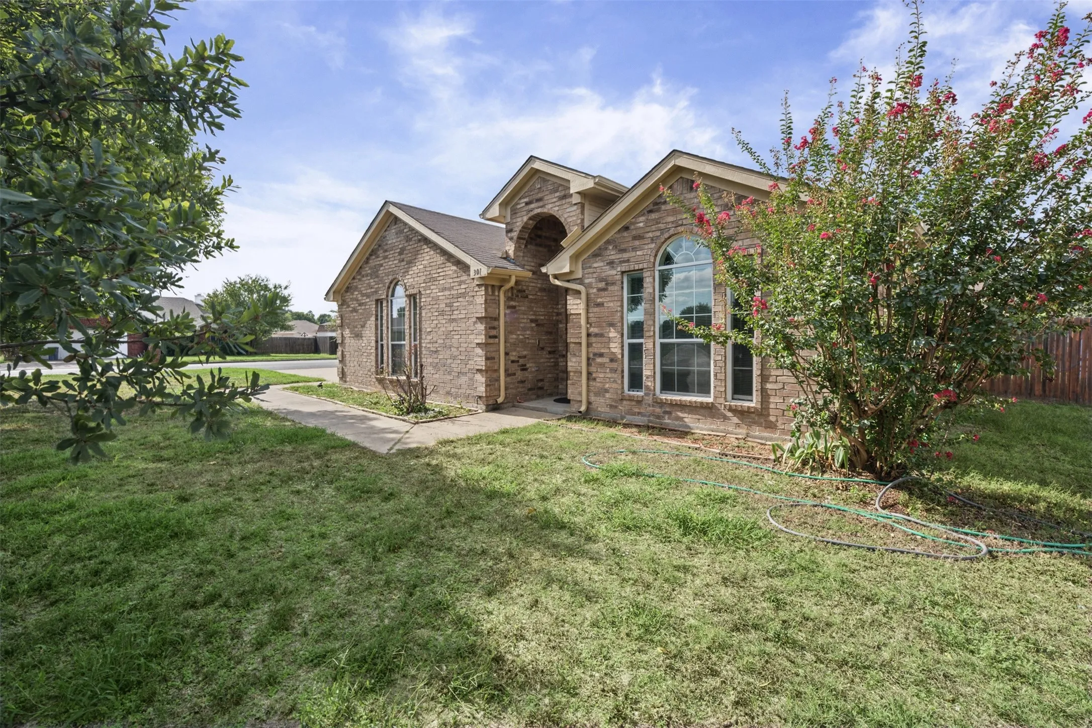 Brick exterior featuring an arched entryway, gabled rooflines, and prominent arched windows