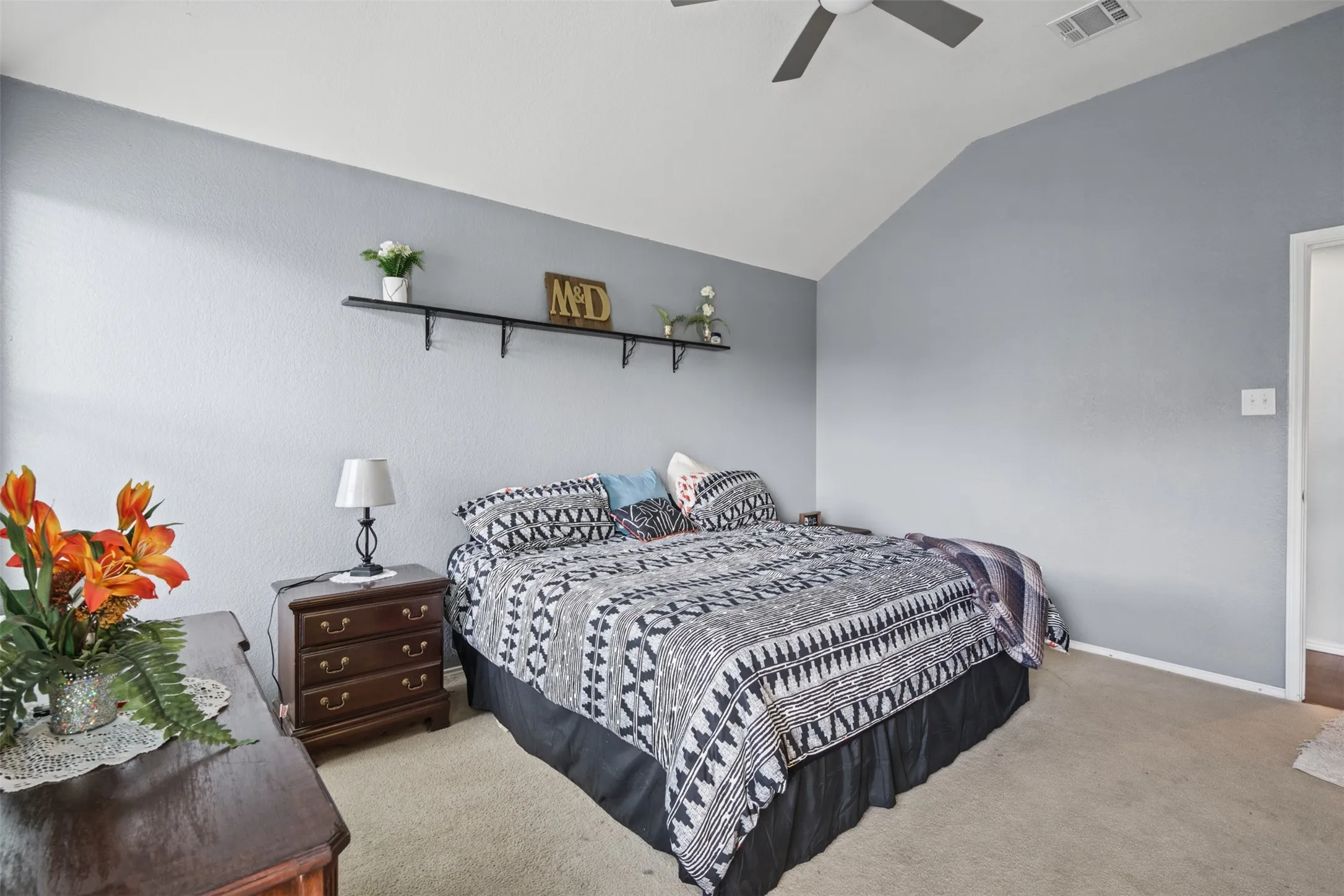 Vaulted ceiling featuring a central matte finish ceiling fan and wall-mounted shelving