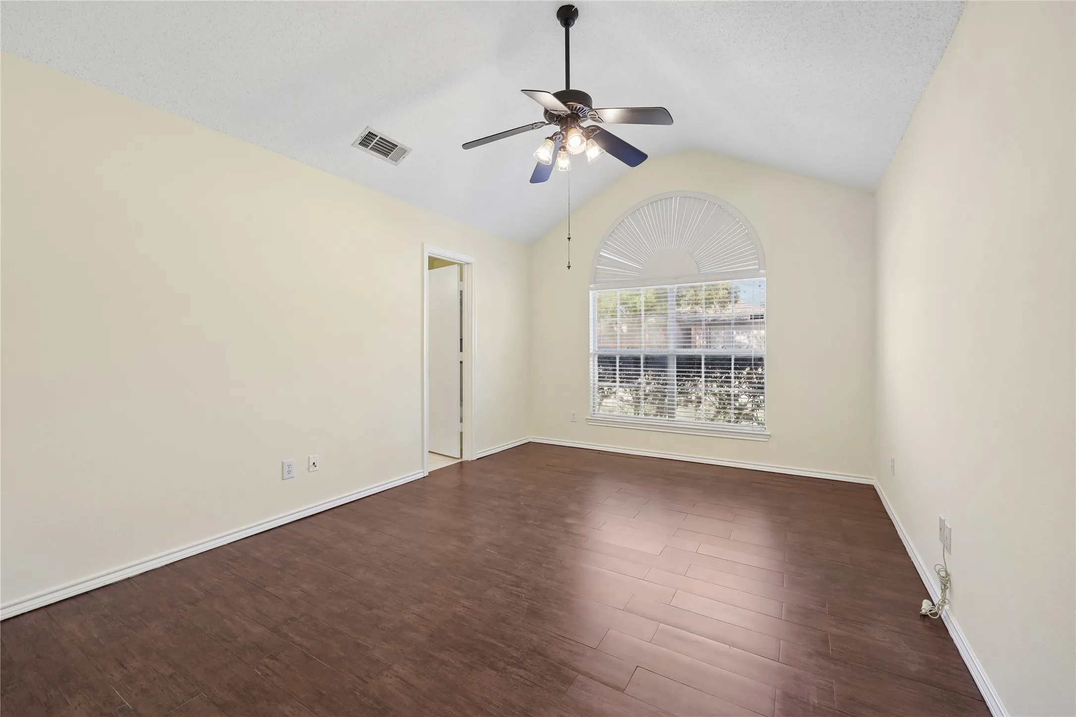 Vaulted ceiling, wood-finish flooring, and arched window featuring a half-moon transom