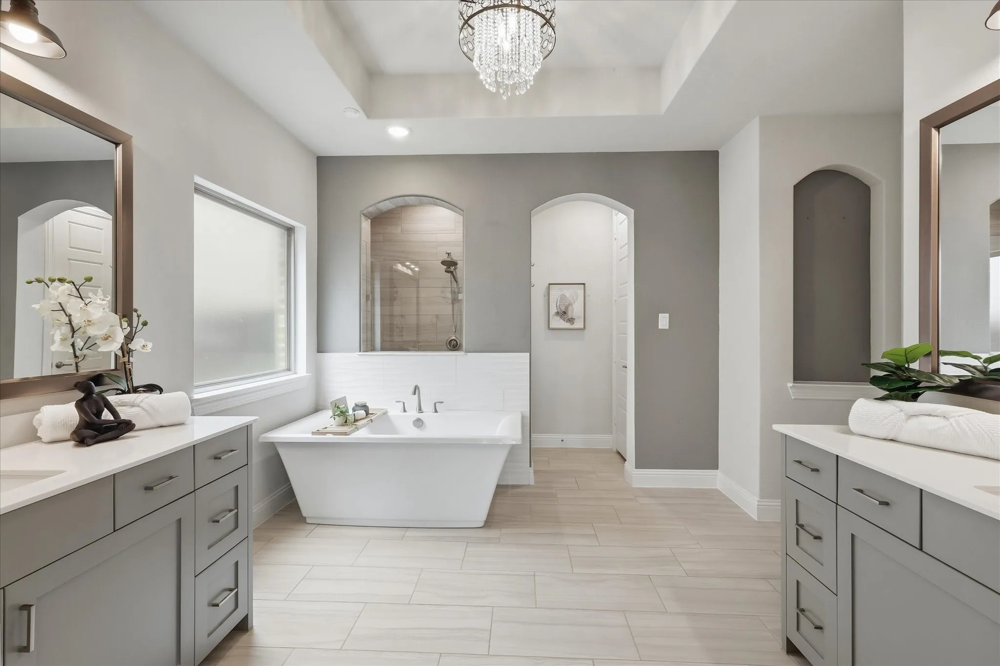 A spa-like primary bathroom offering dual vanities, a freestanding soaking tub, a spacious walk-in shower, and a massive closet with direct, convenient access to the laundry room.
