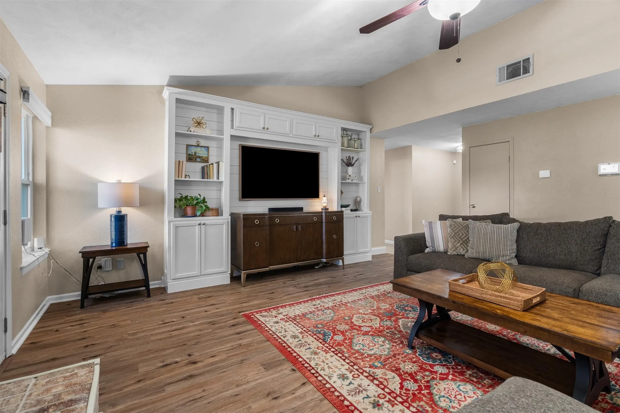 A wall of white built-ins frames the TV.