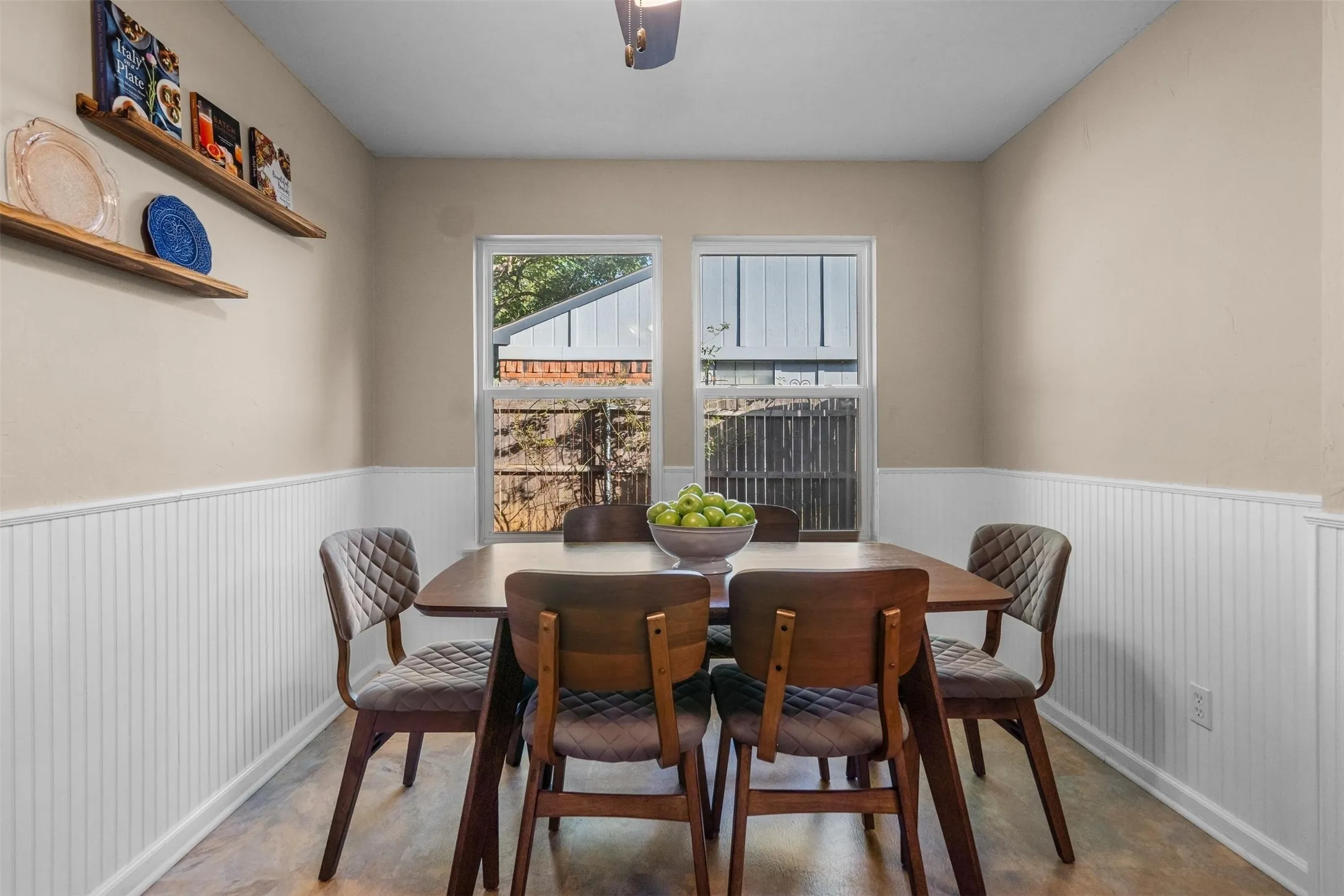 Dining area with wainscoting and two windows.
