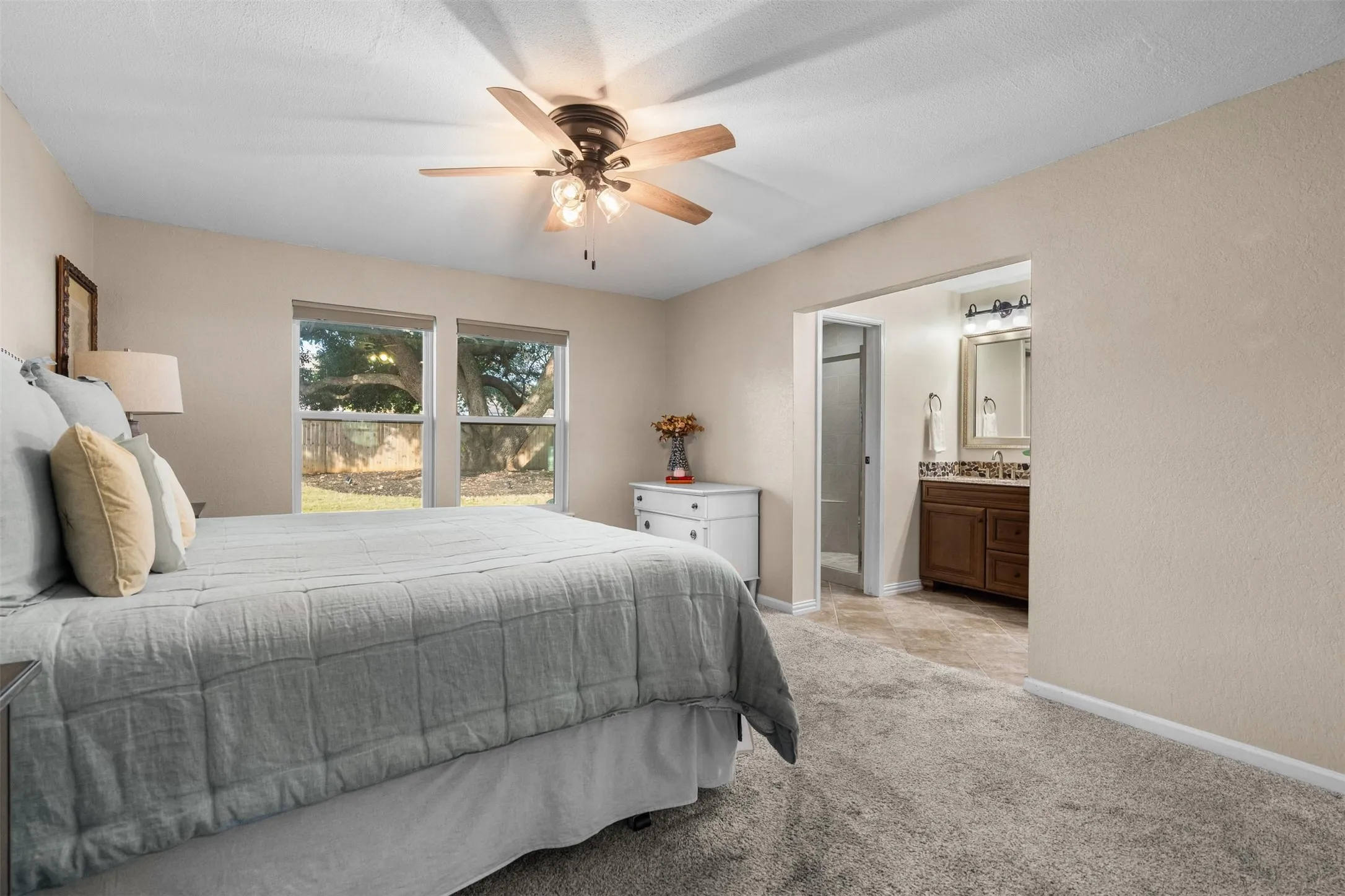 Primary bedroom with a view of the backyard oak.