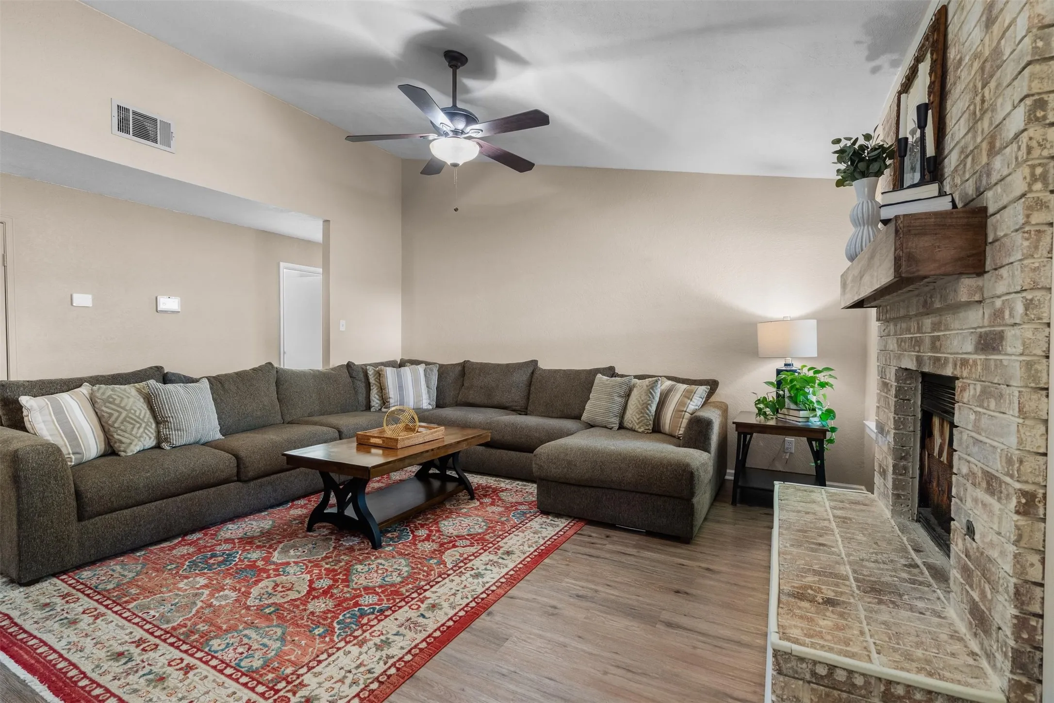 Living room with a vaulted ceiling and a brick fireplace.