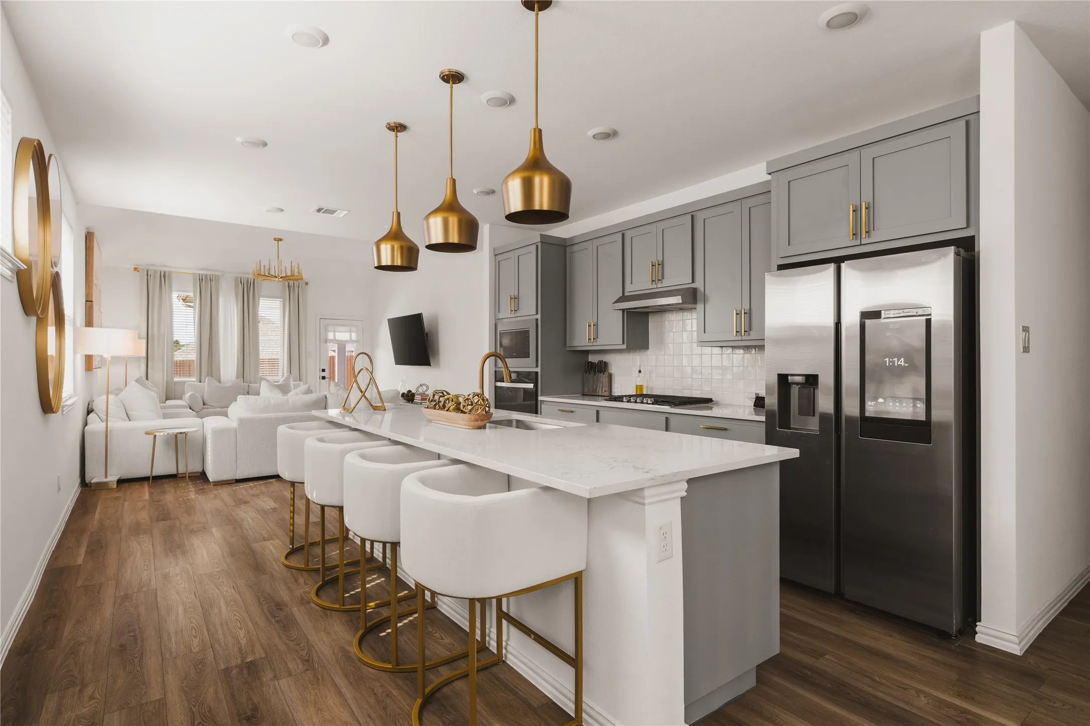 Kitchen featuring gray shaker-style cabinetry, quartz countertops, an expansive center island, wood-finish flooring, and metallic pendant lighting