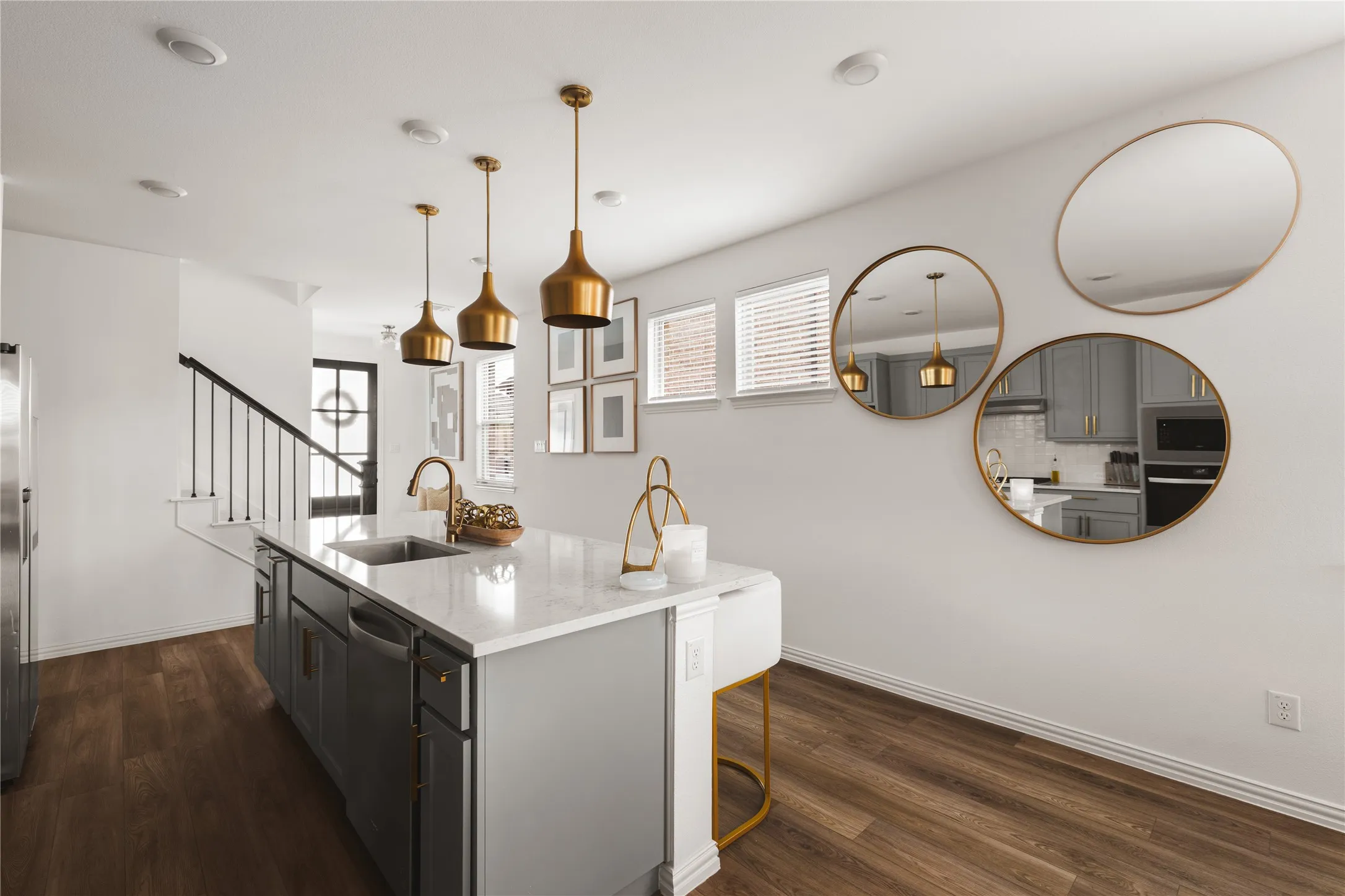 Kitchen island featuring light-toned stone-finish countertop, dual-tone cabinetry, recessed lighting, wood-finish flooring, and metallic pendant fixtures