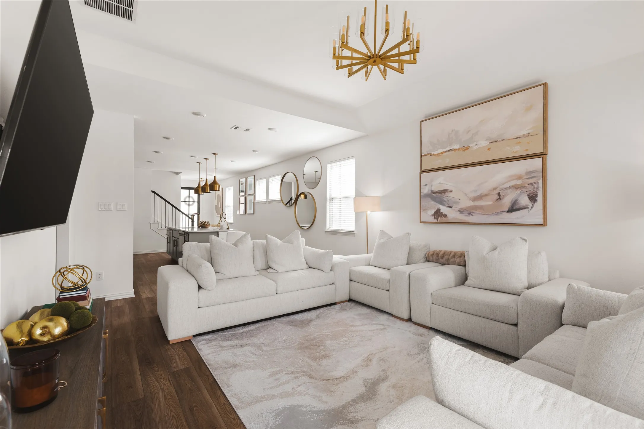 Open-concept living space featuring wood-finish flooring, a multi-arm metallic chandelier, recessed lighting, and a metal-railed staircase