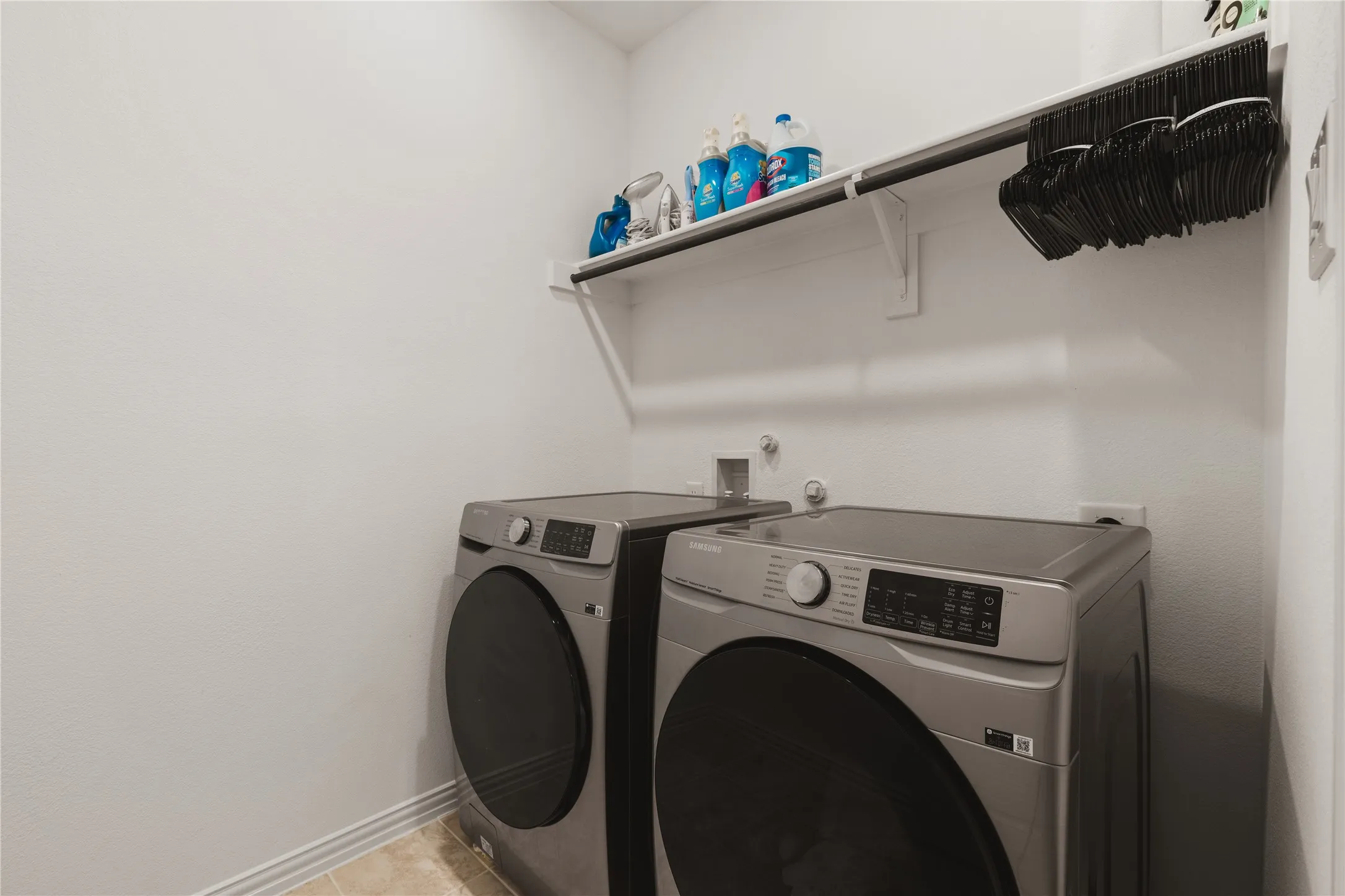 Dedicated utility area featuring a mounted upper storage shelf with integrated hanging rod