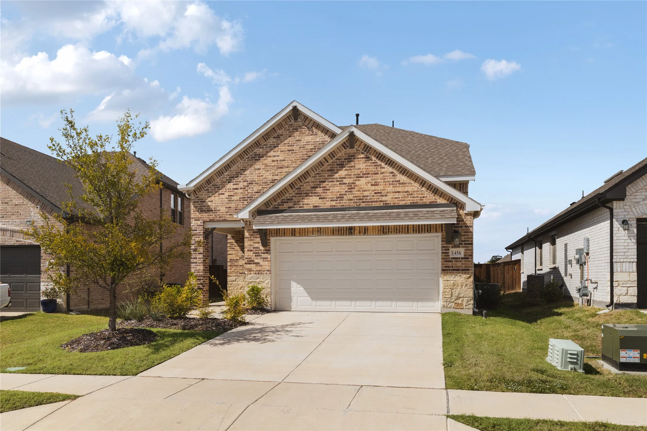 Brick and stone masonry facade with a covered entryway and attached two-car garage
