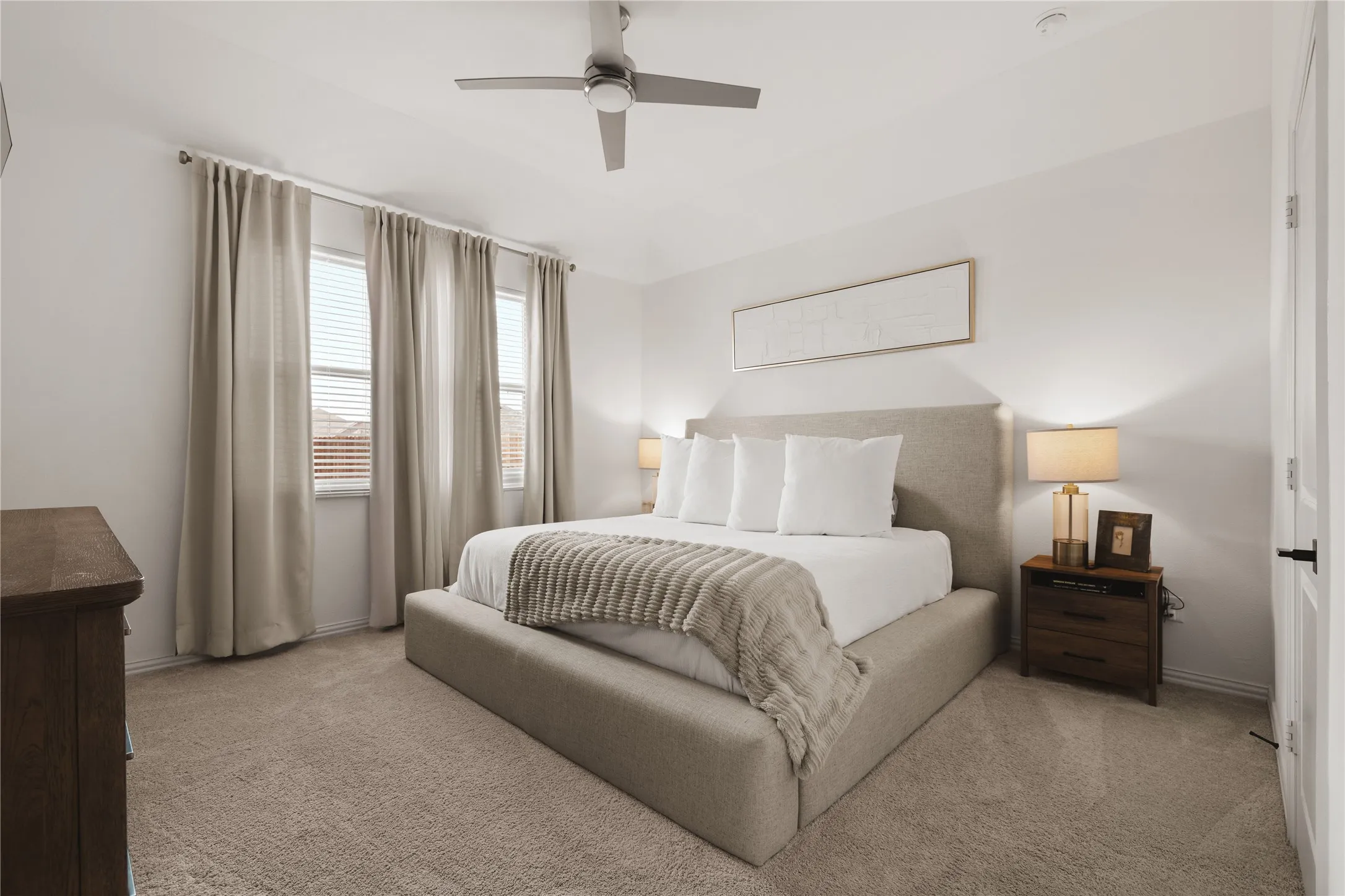 Neutral-toned wall-to-wall carpeting, multi-pane windows, and a brushed metal ceiling fan with integrated lighting