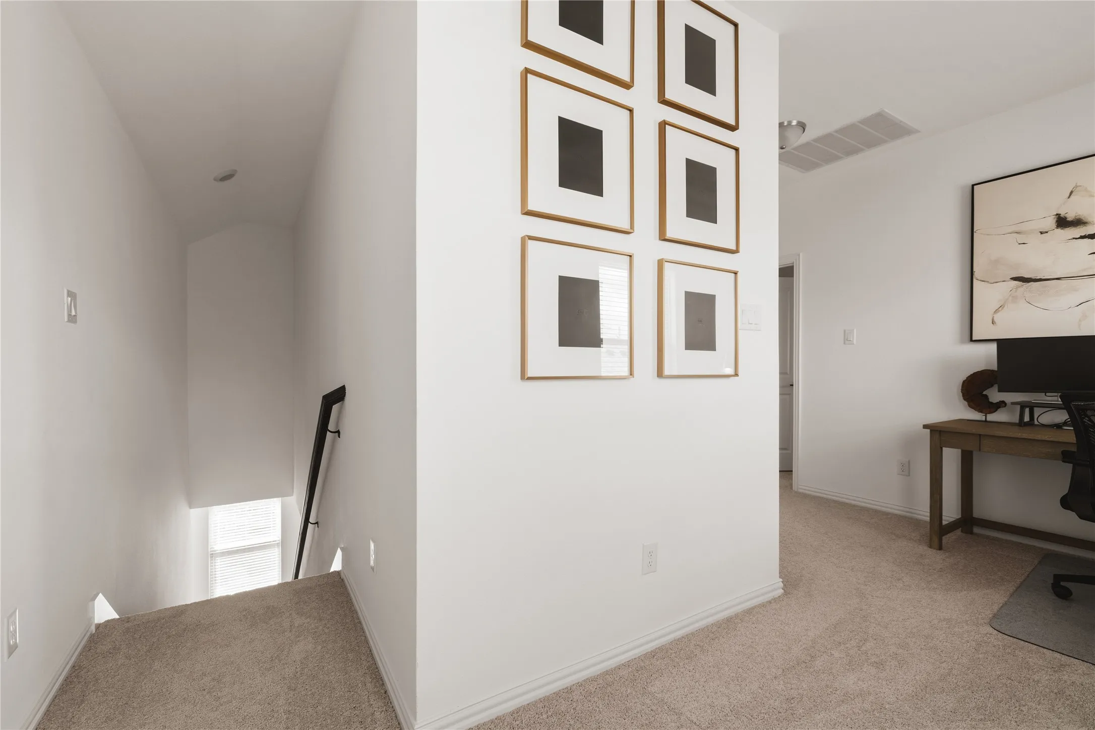 Neutral wall-to-wall carpeting, staircase with black metal handrail, and arched ceiling detail
