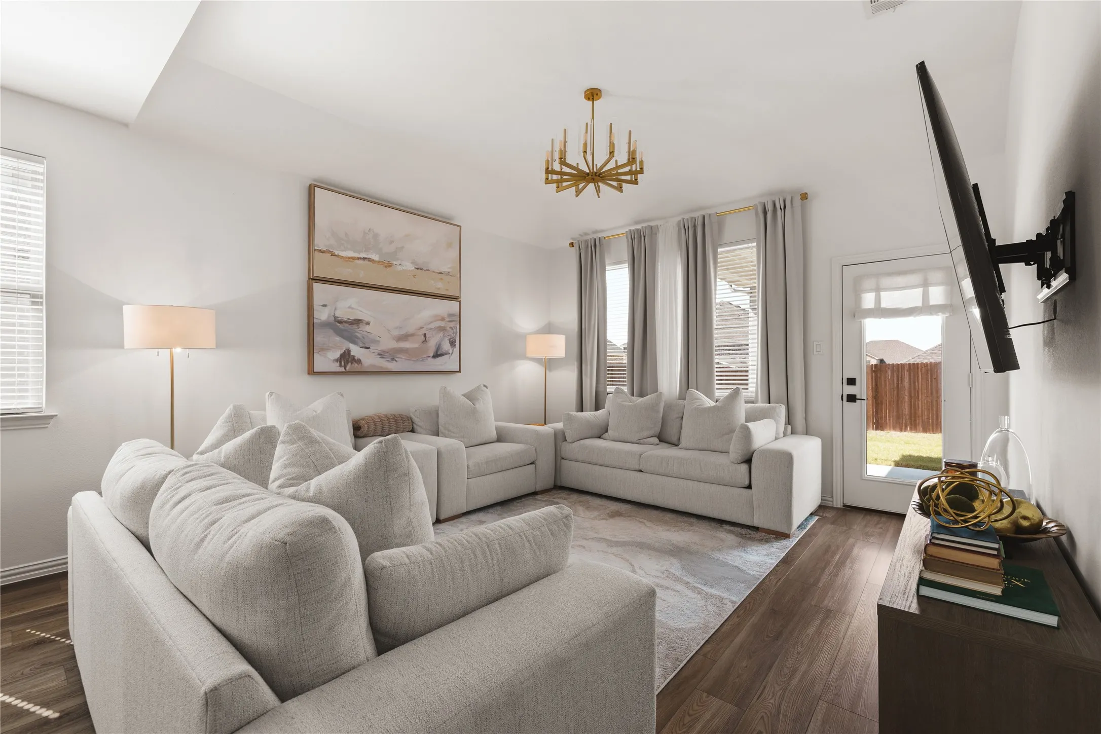 Living area featuring wood-finish flooring, a multi-arm metallic chandelier, and a glass-paneled exterior door