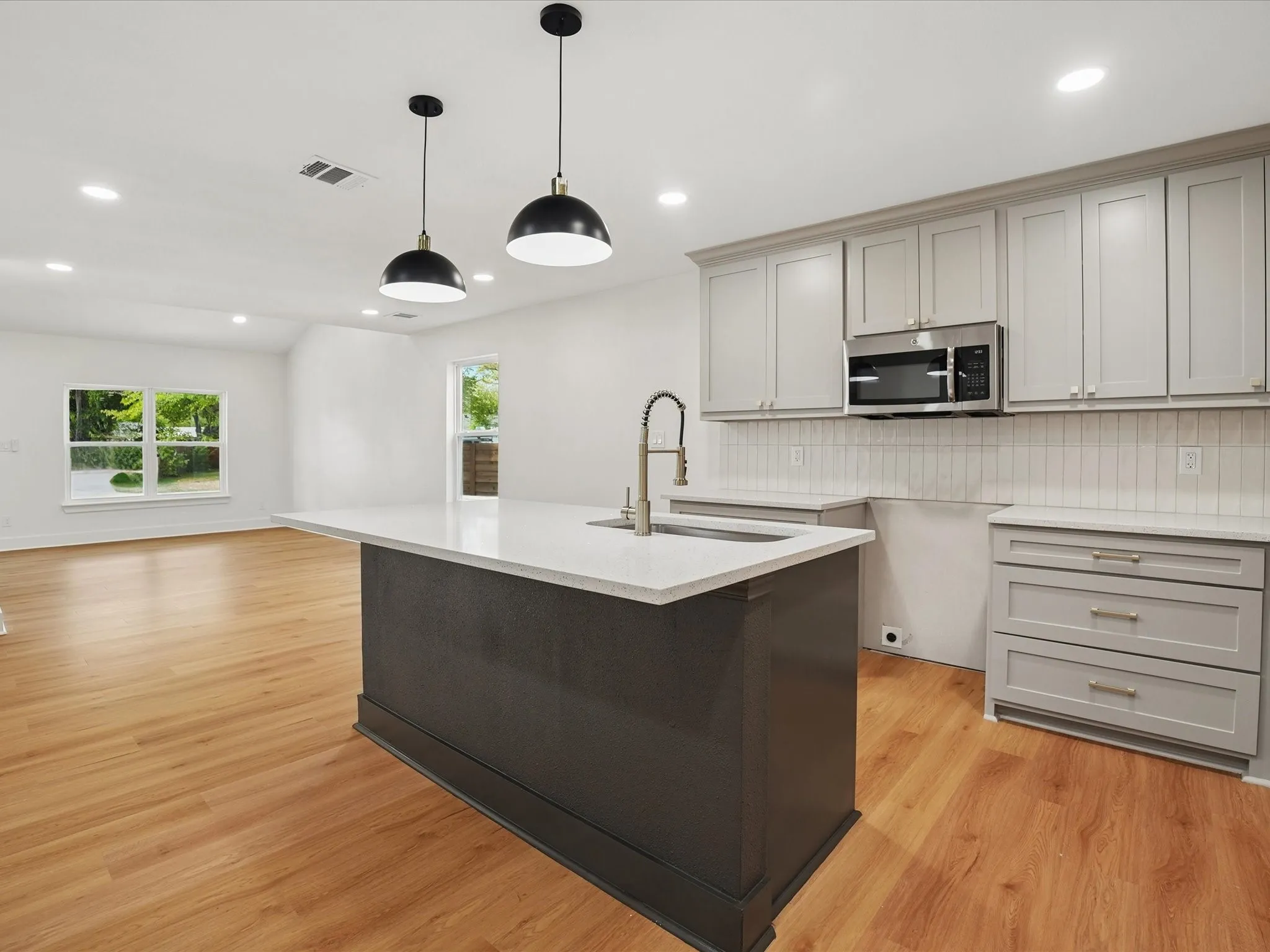 Kitchen featuring a center island with a stone-finish countertop, shaker-style cabinetry, recessed lighting, dual pendant light fixtures, and wood-finish flooring