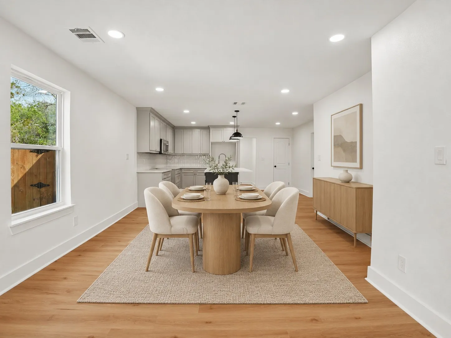 Open-concept interior featuring light wood-finish flooring, recessed lighting, and kitchen cabinetry with a contrasting island