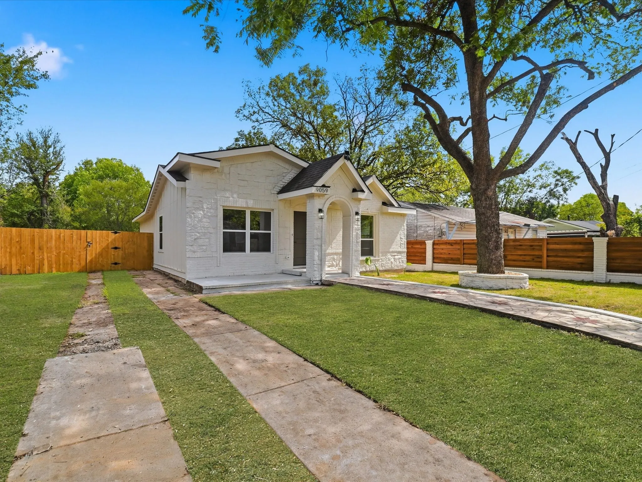 Exterior featuring a textured stone facade, a covered entryway with an arched portico, and wood-finish horizontal privacy fencing