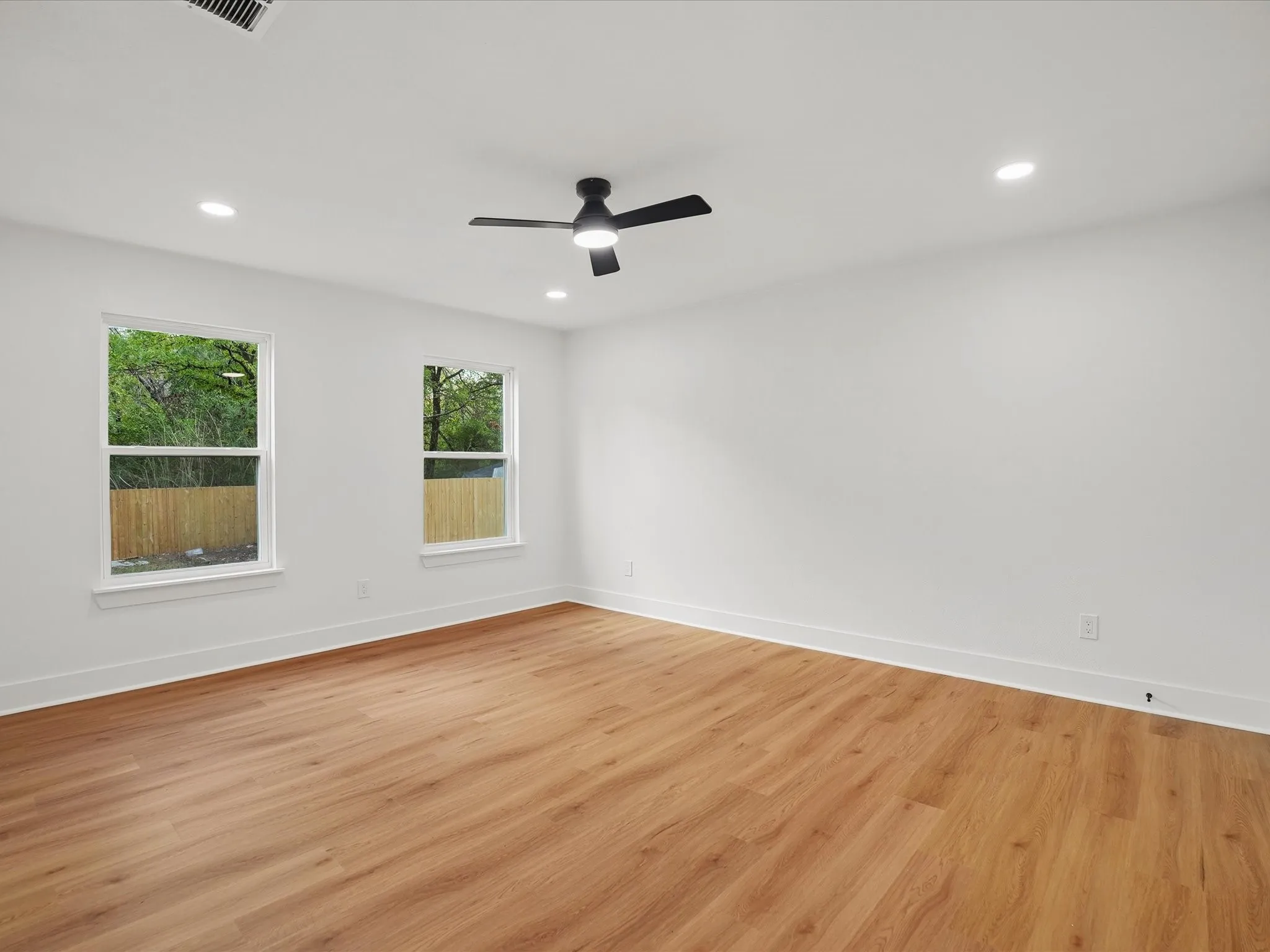 Room featuring wood-finish flooring, recessed lighting, matte black ceiling fan, and dual pane windows
