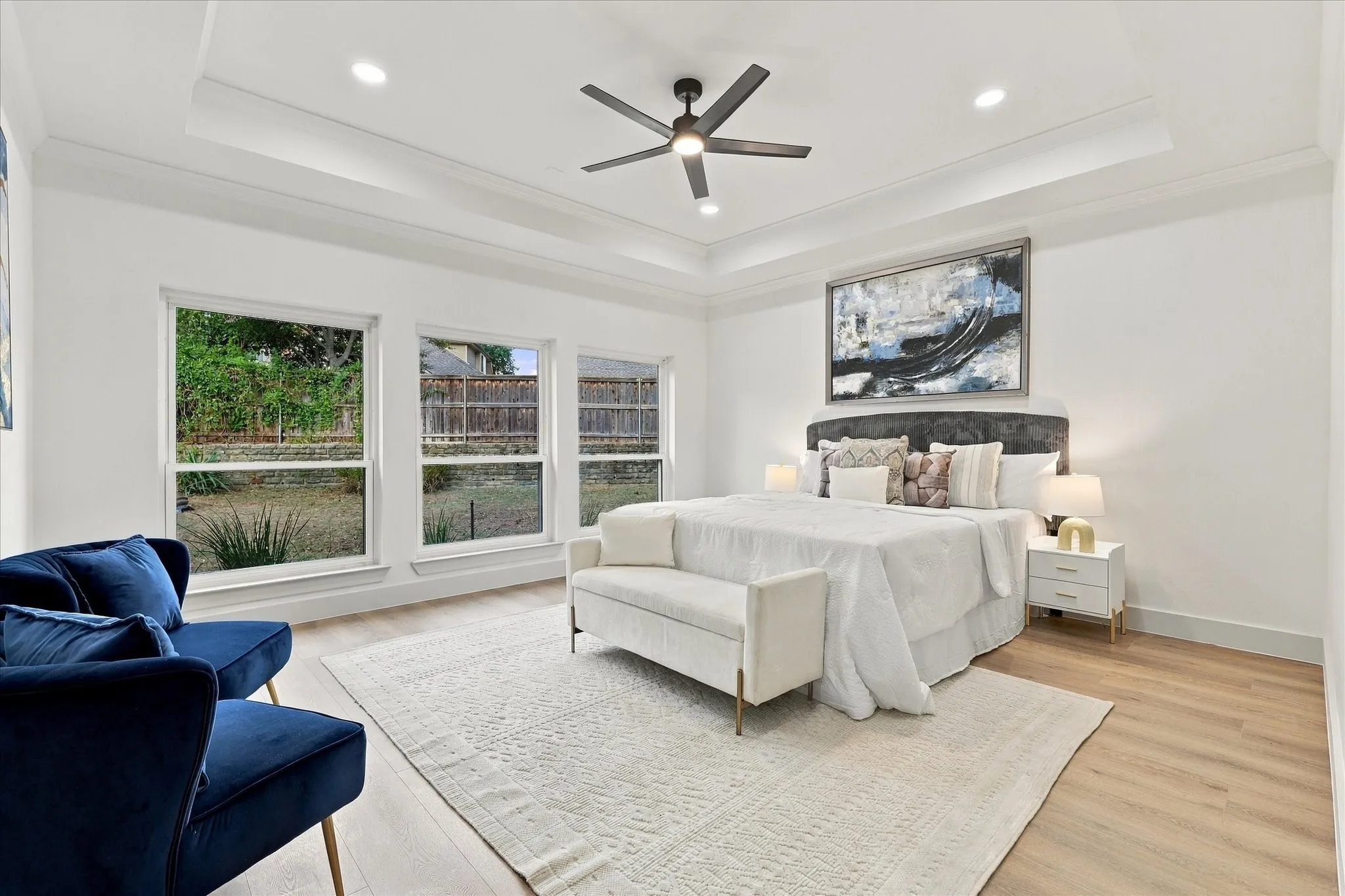 Tray ceiling with recessed lighting, wood-finish flooring, and expansive windows
