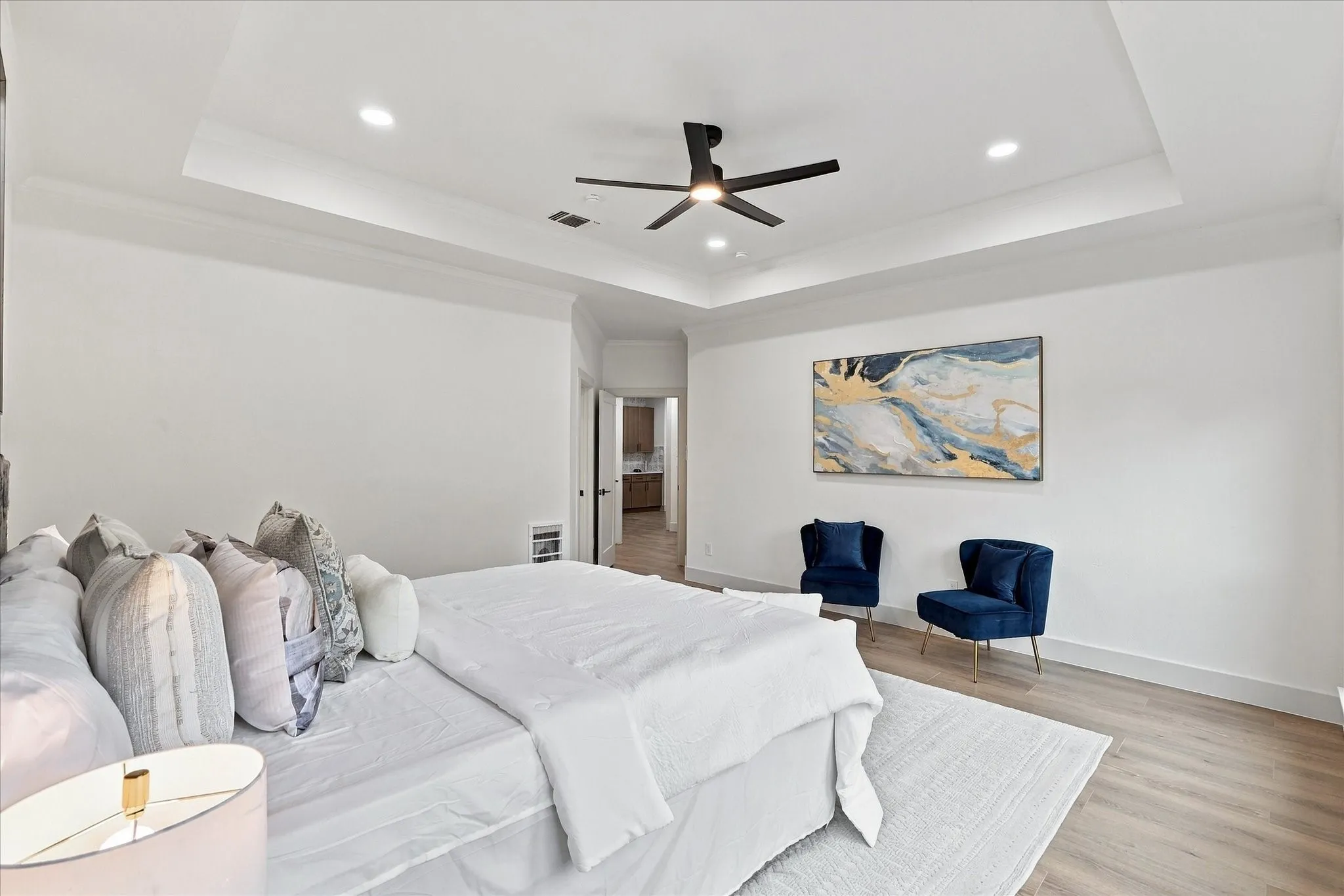 Tray ceiling featuring recessed lighting and a central matte black ceiling fan, complemented by wood-finish flooring