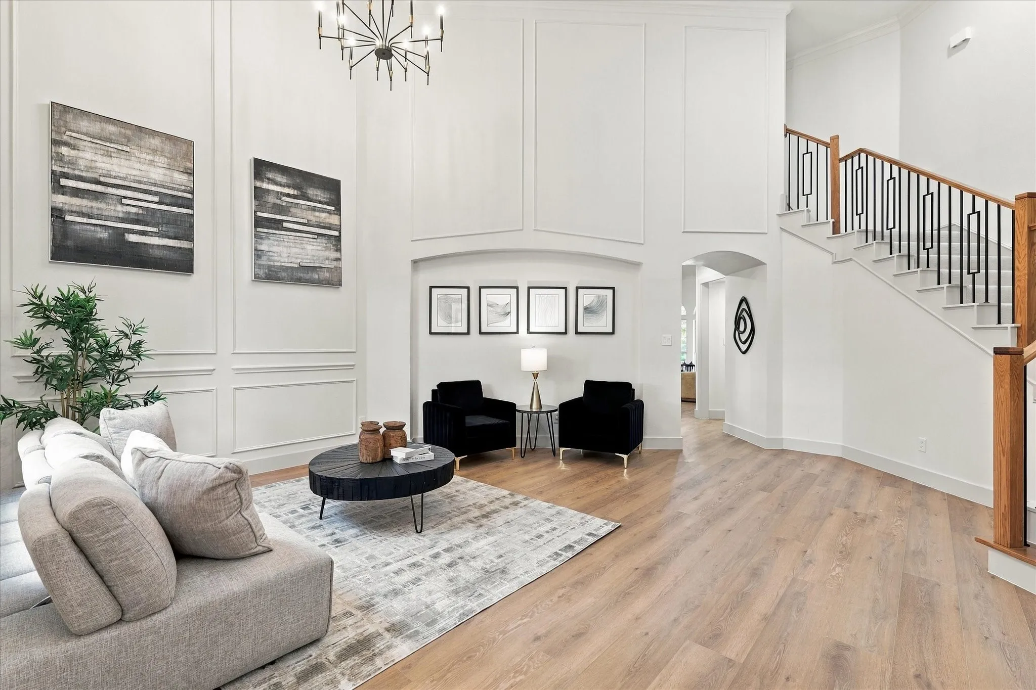 Two-story foyer featuring paneled walls, wood-finish flooring, a tiered chandelier, and a staircase with metal balusters and wood handrails
