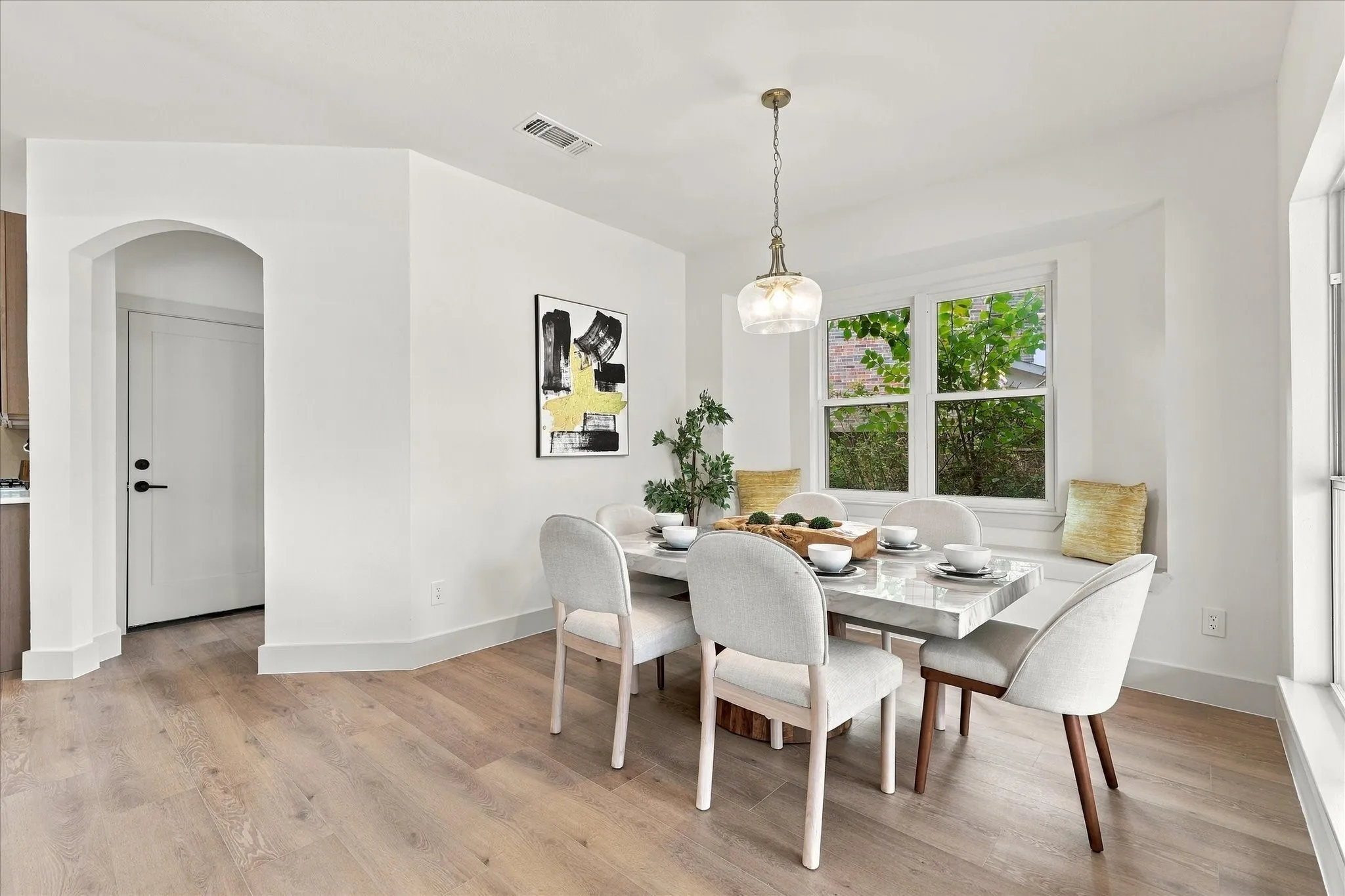 Dining area featuring wood-finish flooring, a built-in window seat, an arched doorway, and a pendant light fixture