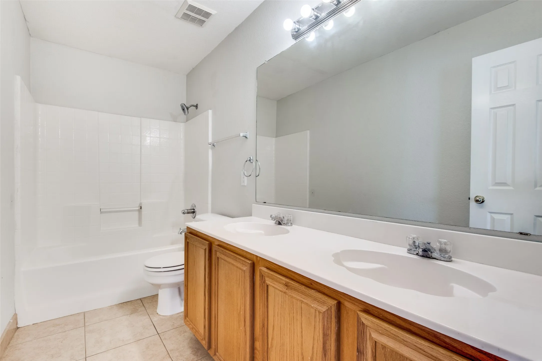 Full bathroom featuring shower / bathtub combination, tile patterned flooring, toilet, and double sink vanity