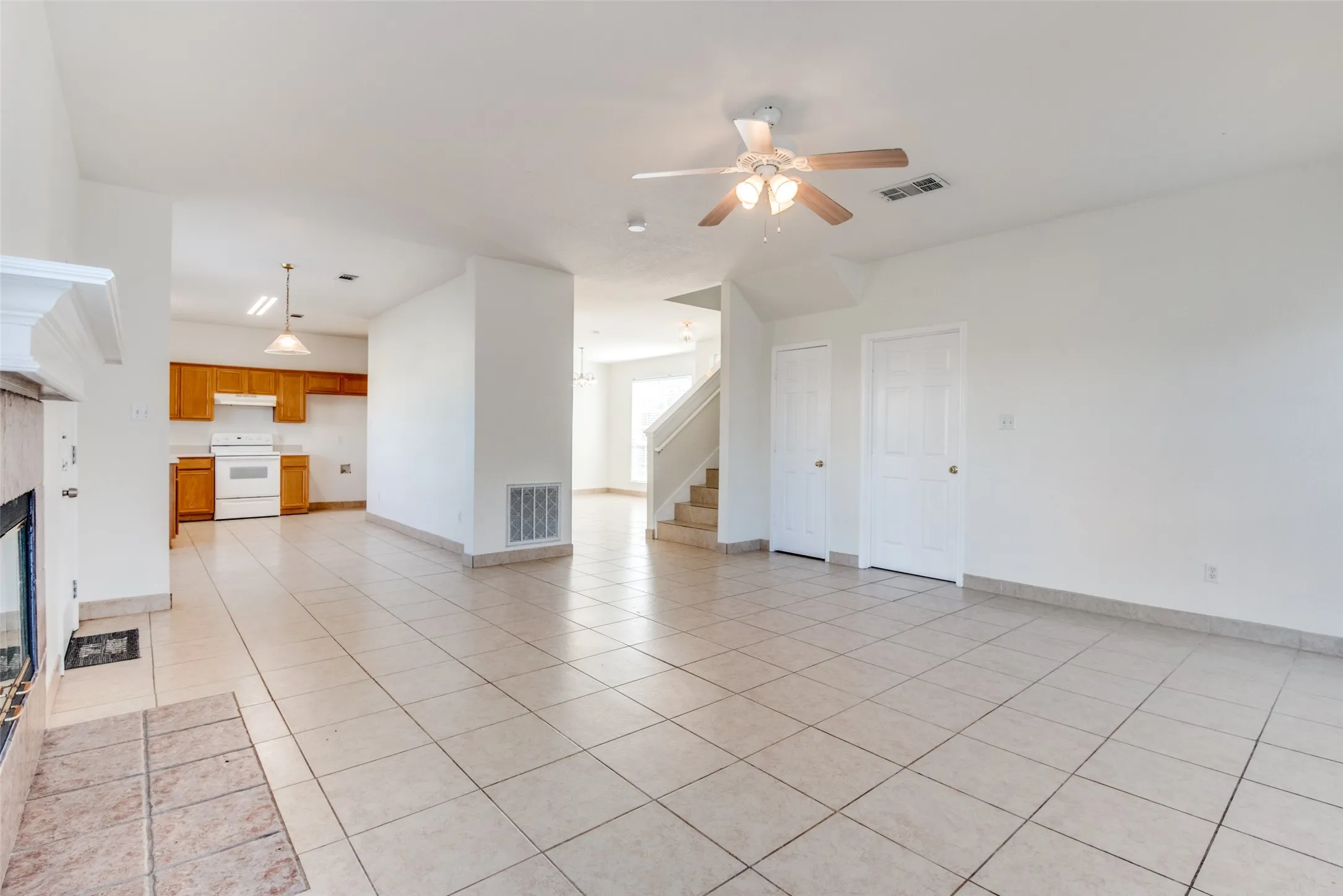 Unfurnished living room with light tile patterned flooring, a fireplace, and ceiling fan